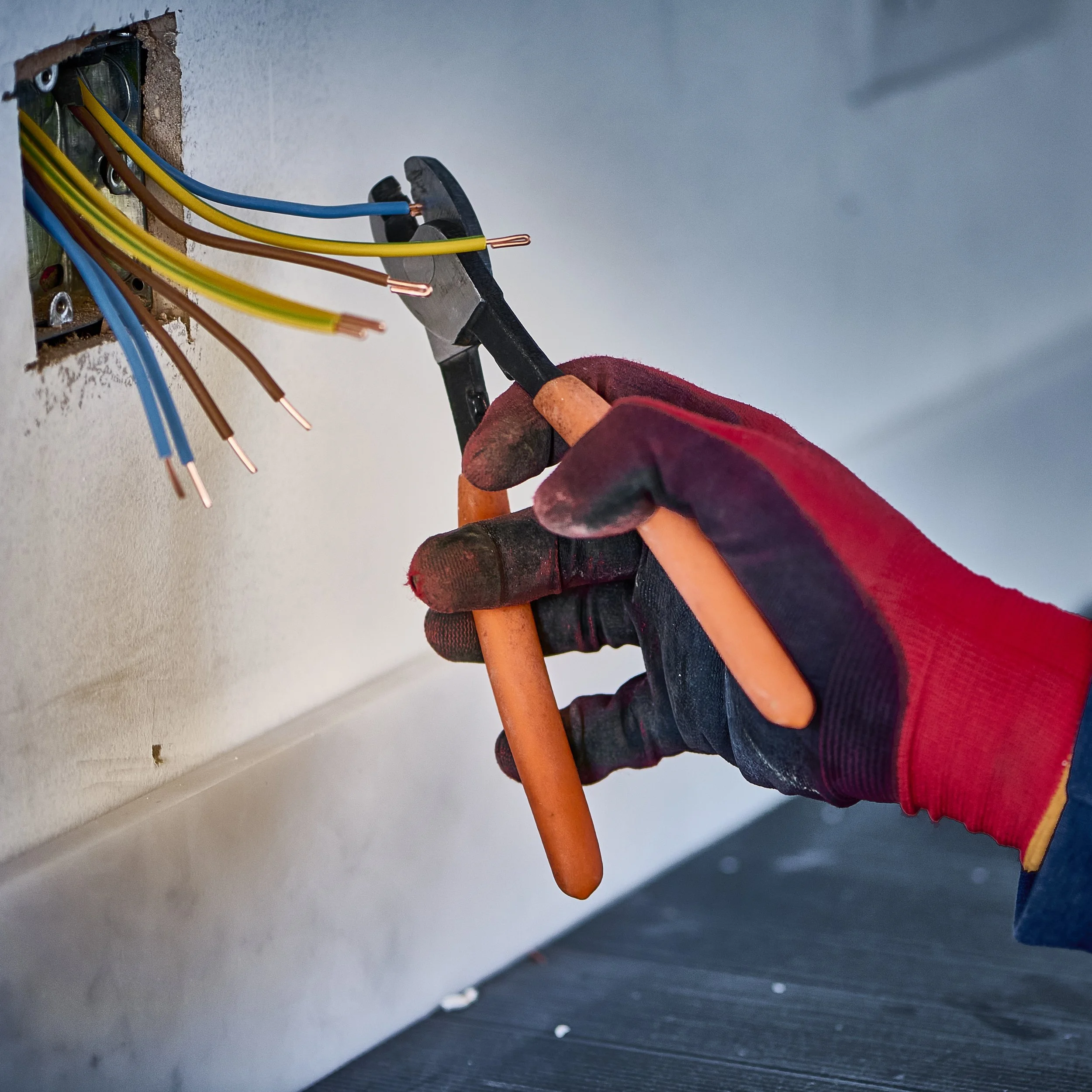 Gloved hand cutting electrical cables with wire cutters