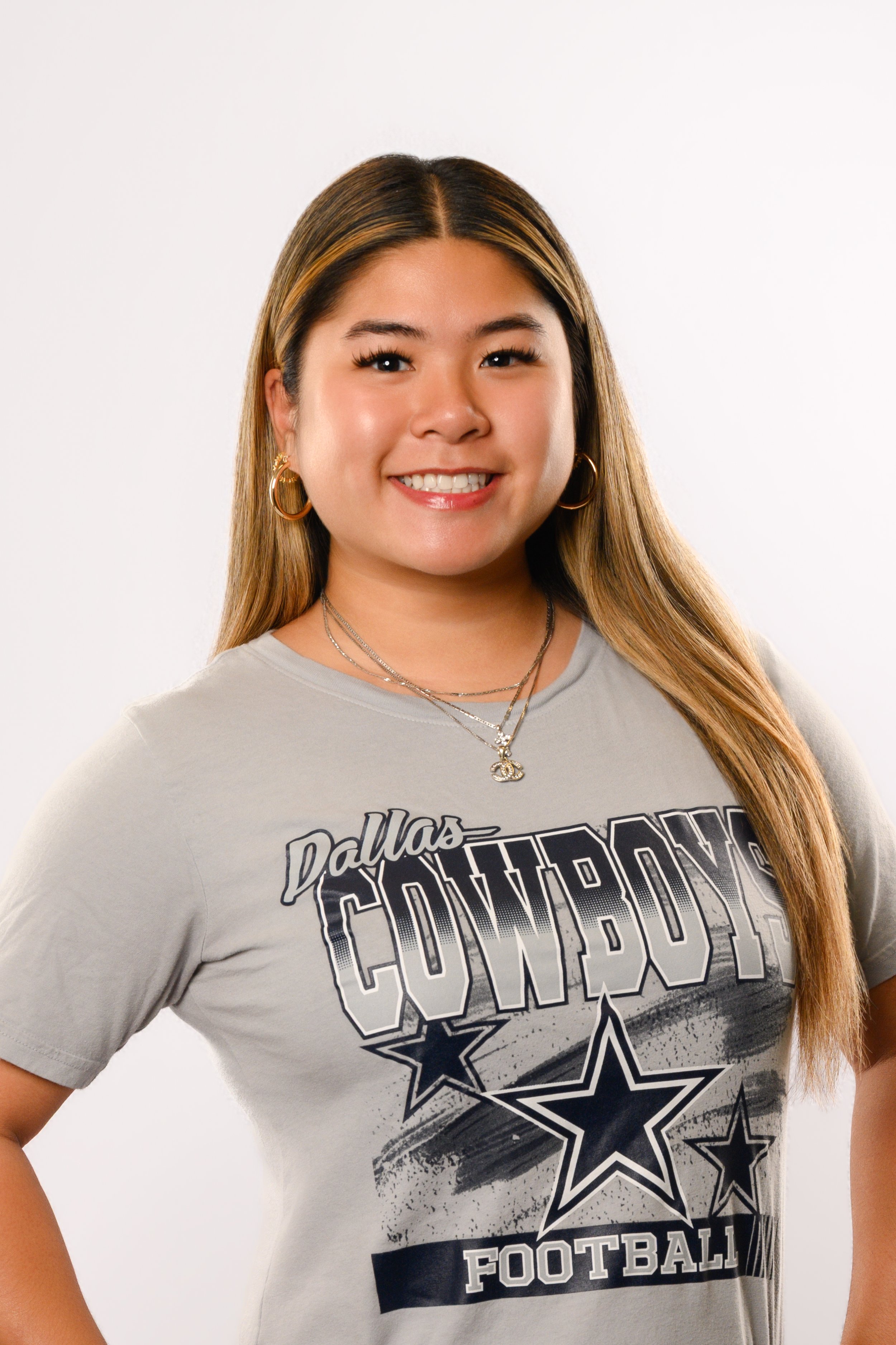 Professional headshot of Dalena, therapy coordinator for Dr. Casper’s office, smiling in a gray Dallas Cowboys t-shirt against a neutral studio background.