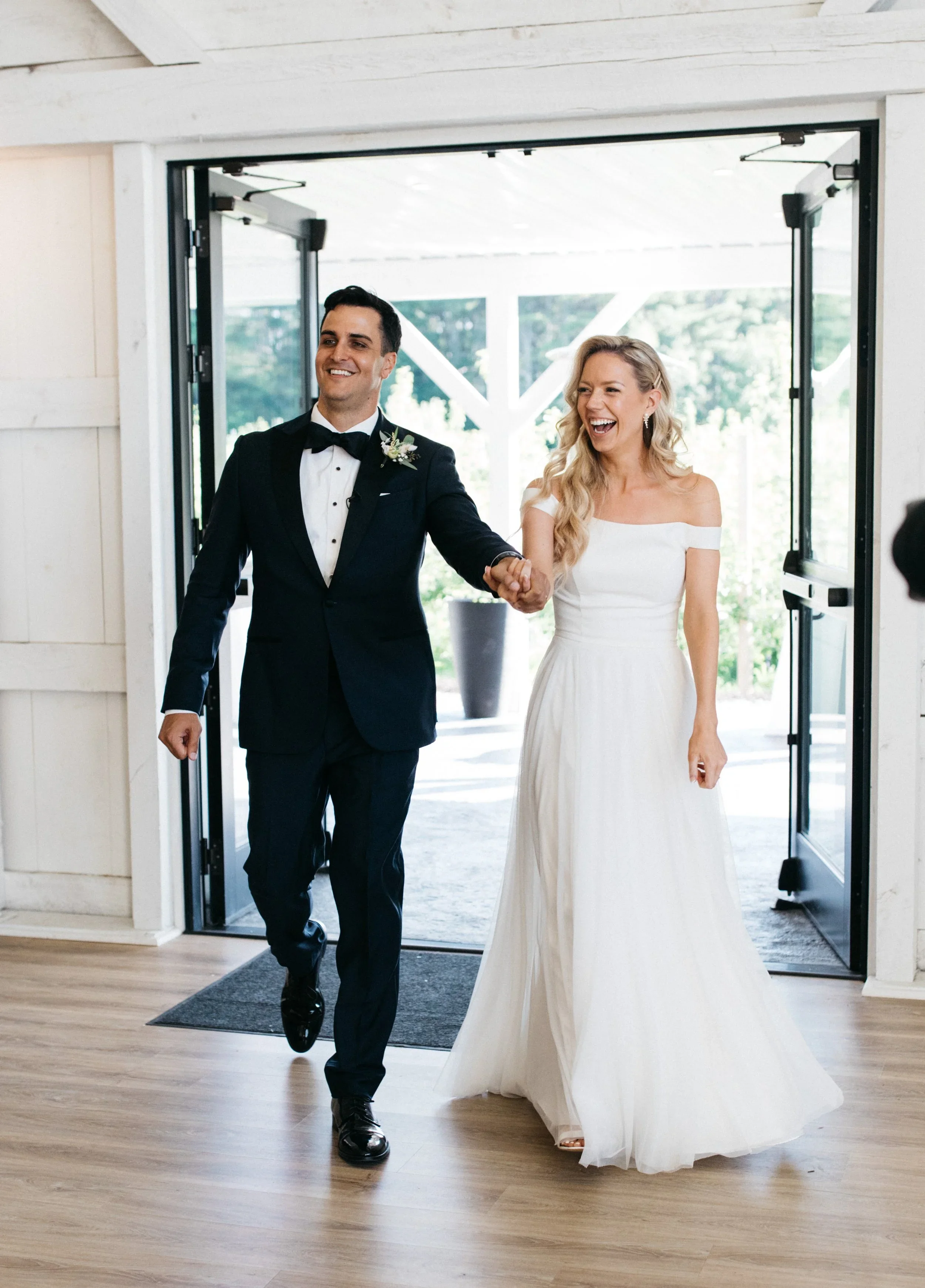 bride and groom joyfully walk into wedding reception