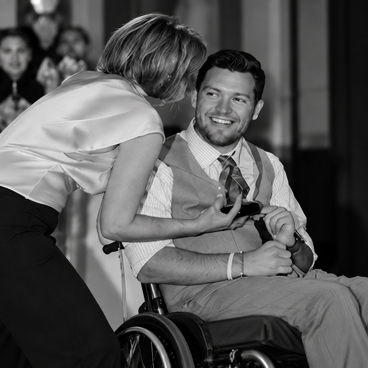 Woman speaking with smiling man seated in wheelchair.png