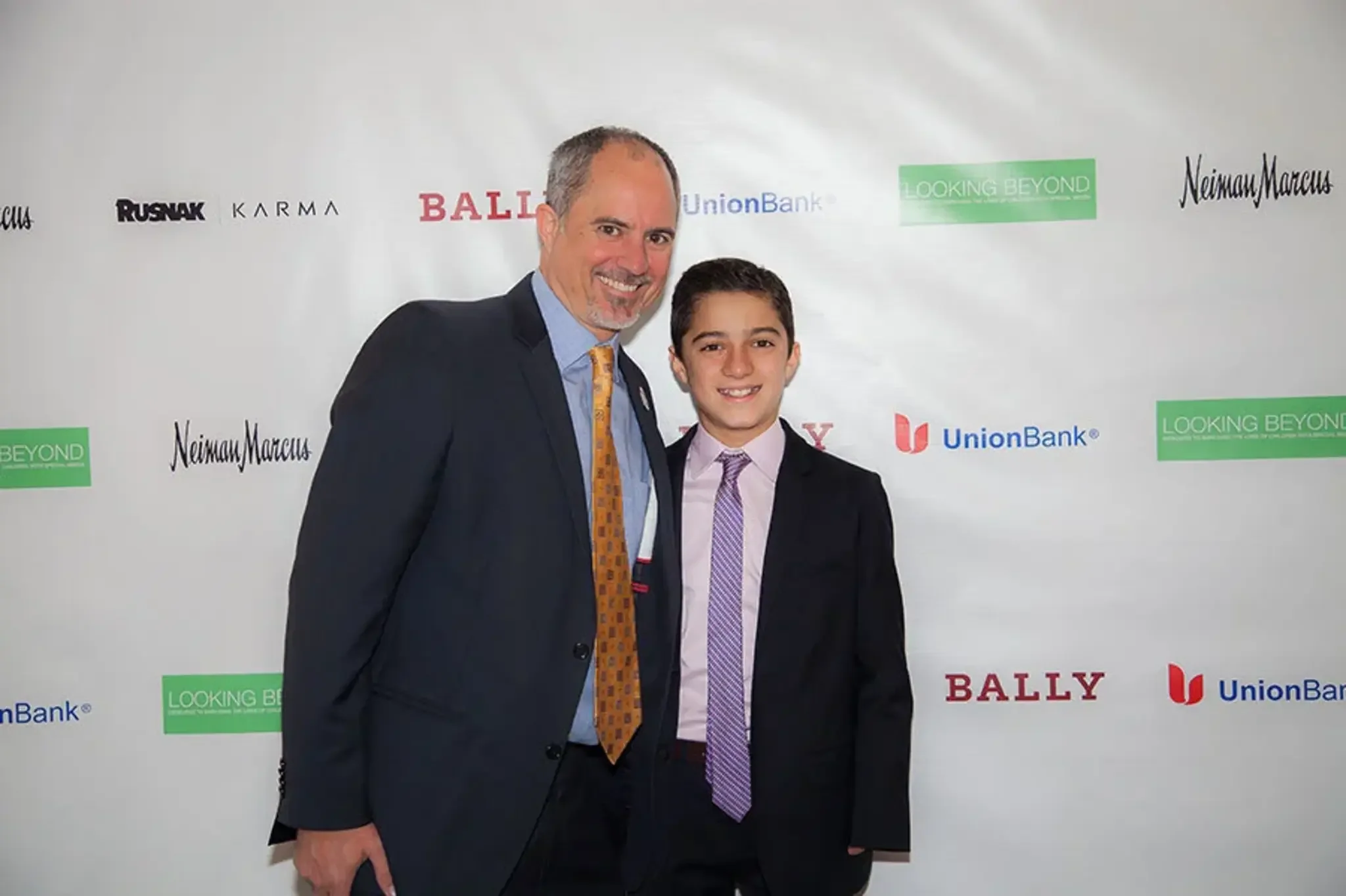 08-man-and-boy-at-sponsor-backdrop.webp