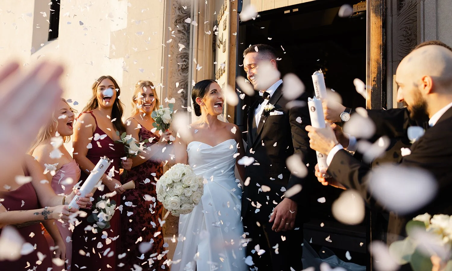 Bride and groom exciting the church with rose petals being tossed.