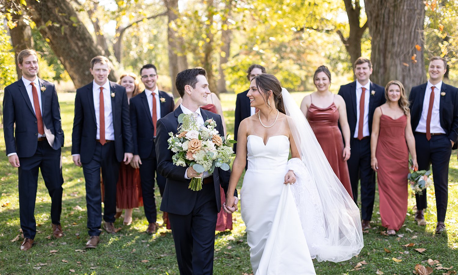 Wedding party walking with groom holding bridal bouquet designed by The Flower Lab in St. Louis.