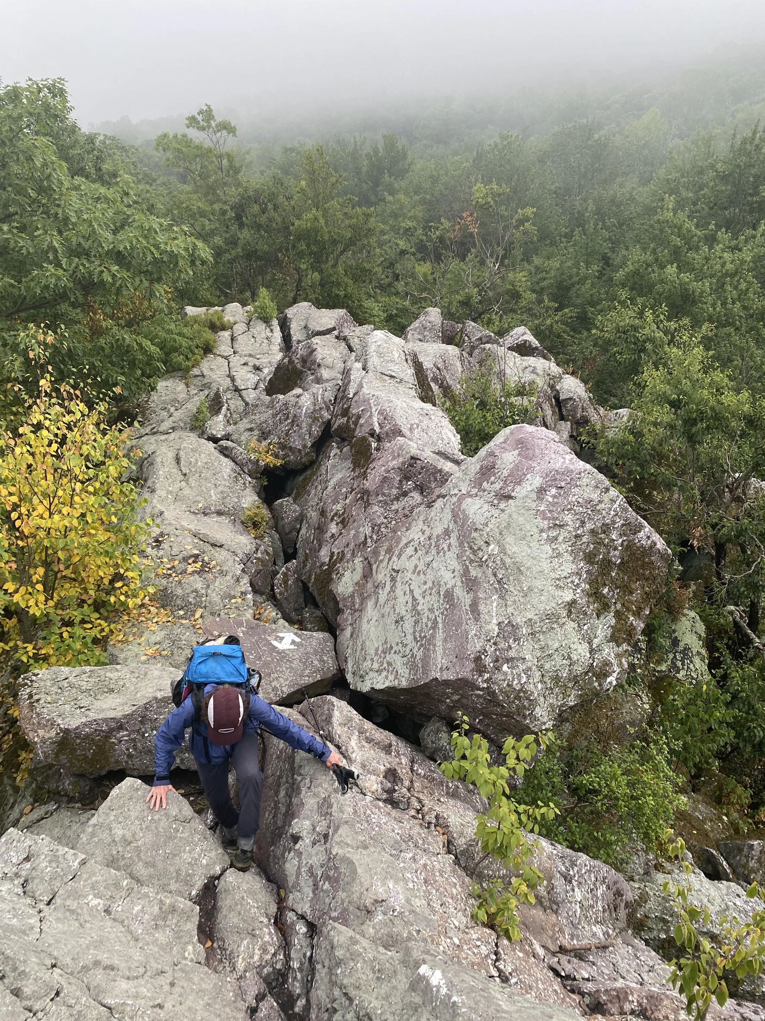 Chili Pepper Woman scrambling across a rock ledge in New York.