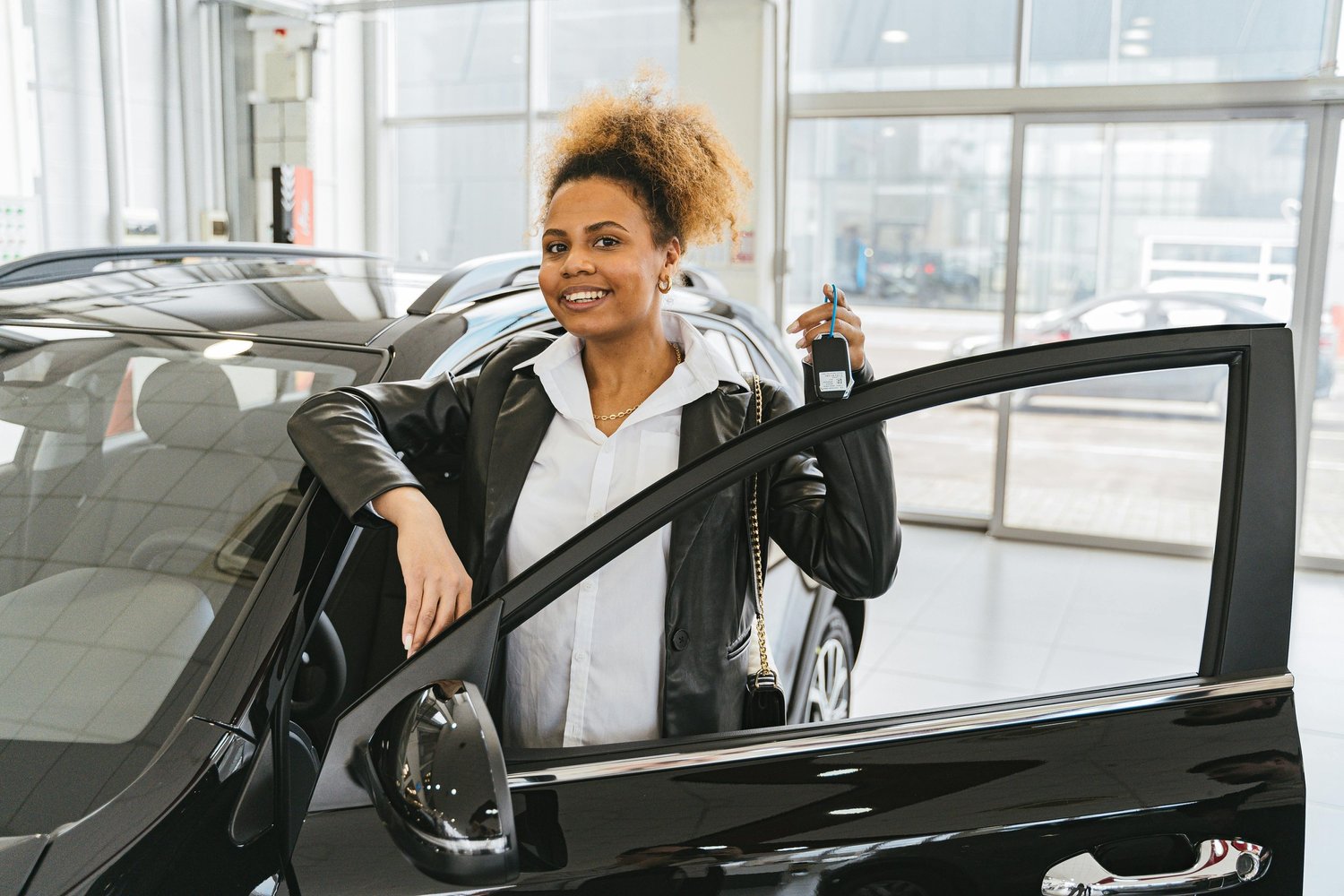 Car keys being handed from one person to another, representing a licensed primary driver taking over a vehicle owned by someone without a license