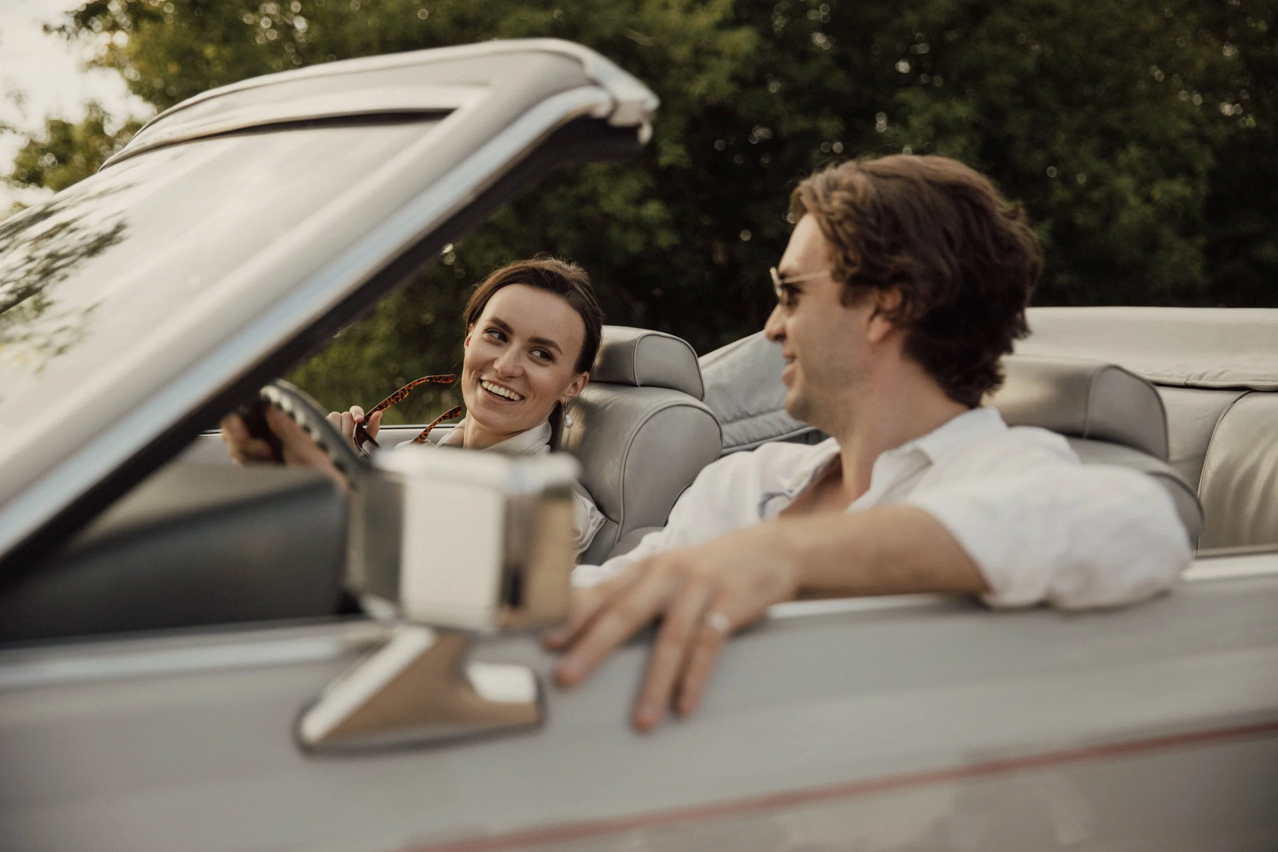 Happy couple riding in a convertible on a sunny day