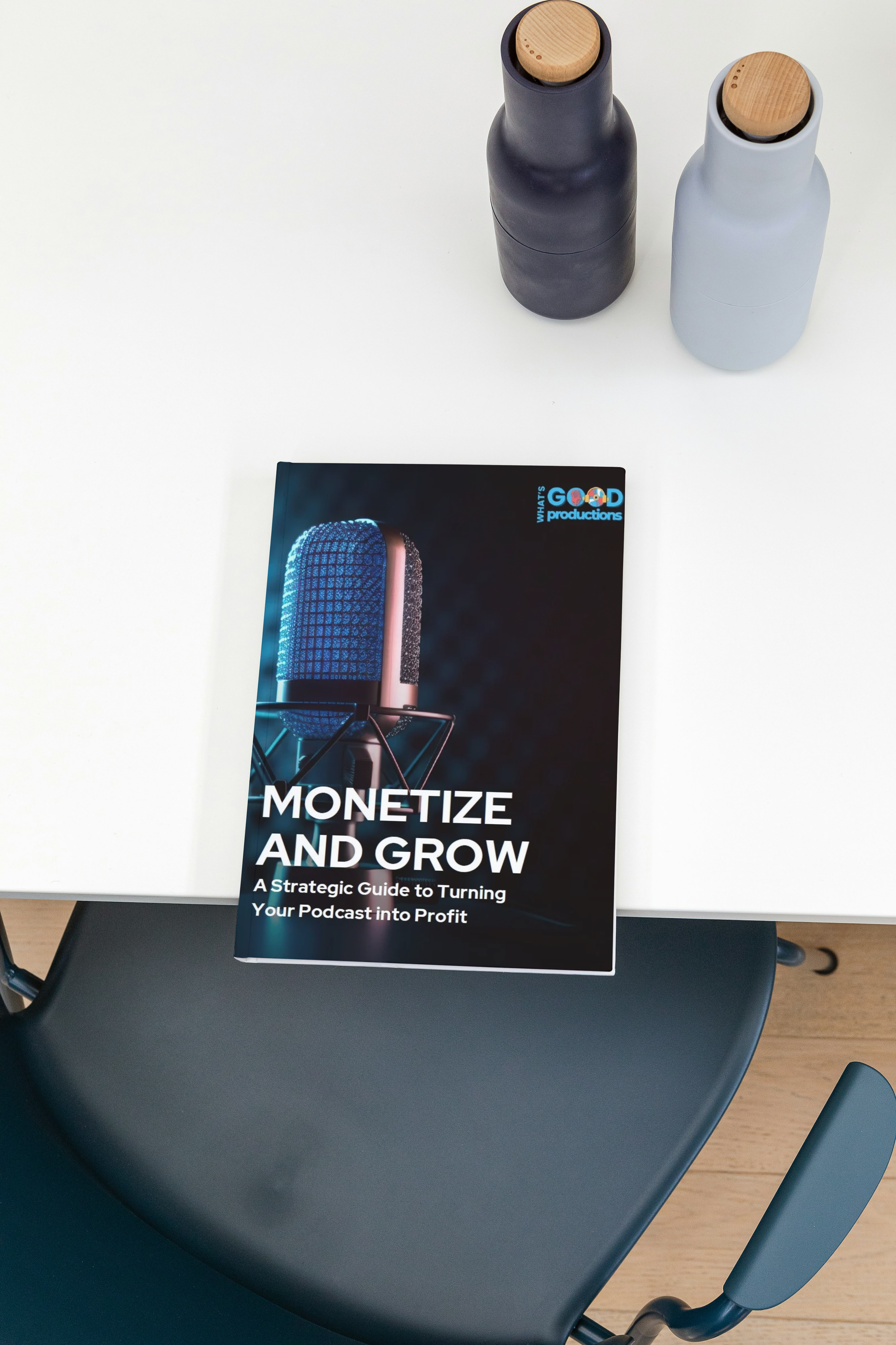 A magazine titled 'Monetize and Grow' on a white table with two bottles with wooden caps and a dark and a light gray color.