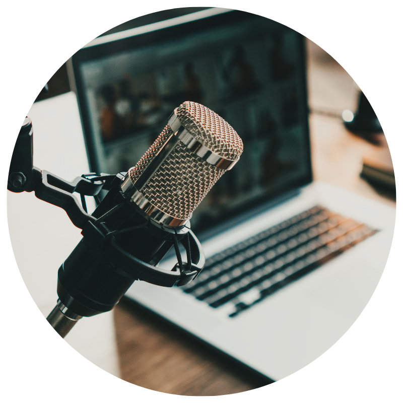 A professional microphone mounted on a stand in front of a laptop on a desk.