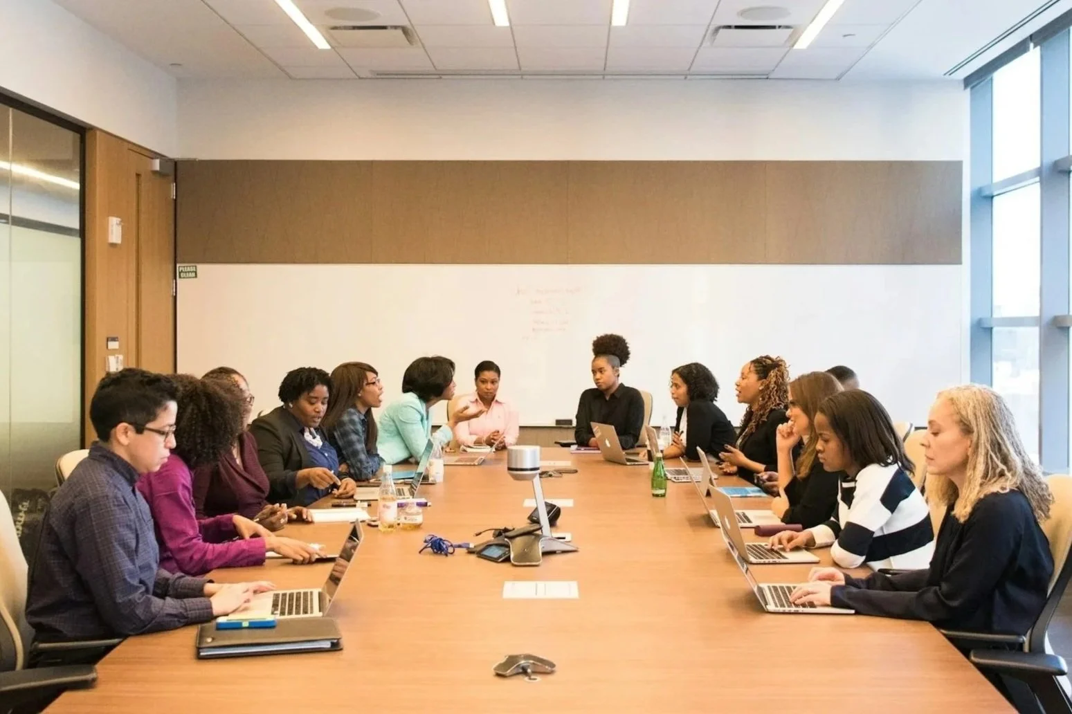 Marinella Hall Associates leading a leadership training in a conference room full of people sitting around a large table with their computers.