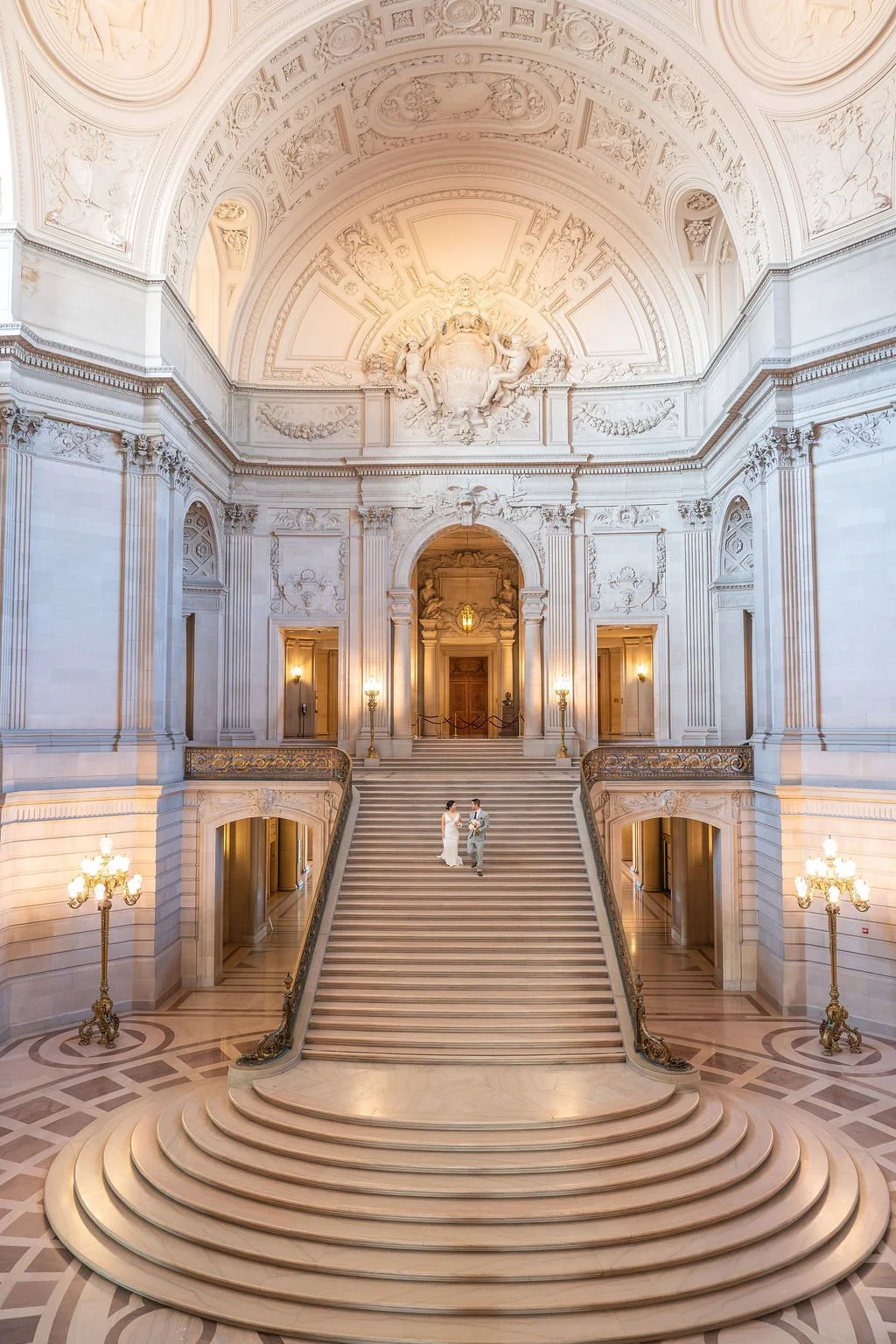 bride and groom holding hands walking down staircase for San Francisco City Hall wedding photography