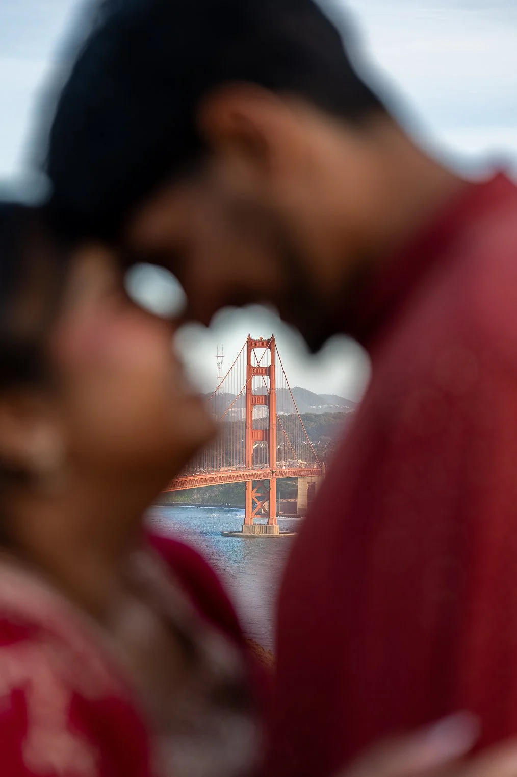 A couple poses together by the Golden Gate Bridge for their San Francisco engagement photos.