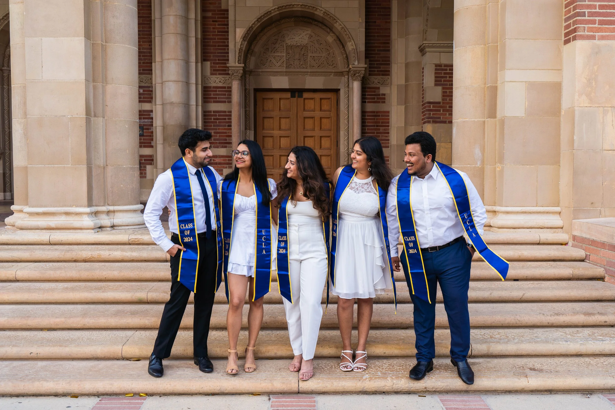 group of five students smiling for UCLA grad photos on campus