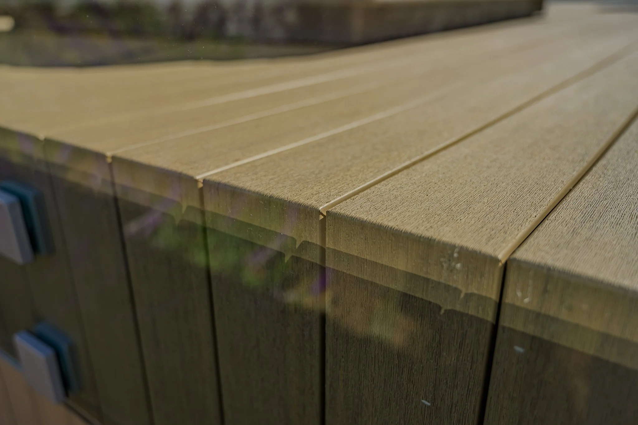 Close-up of a wooden railing or fence with horizontal planks, outdoors on a sunny day.