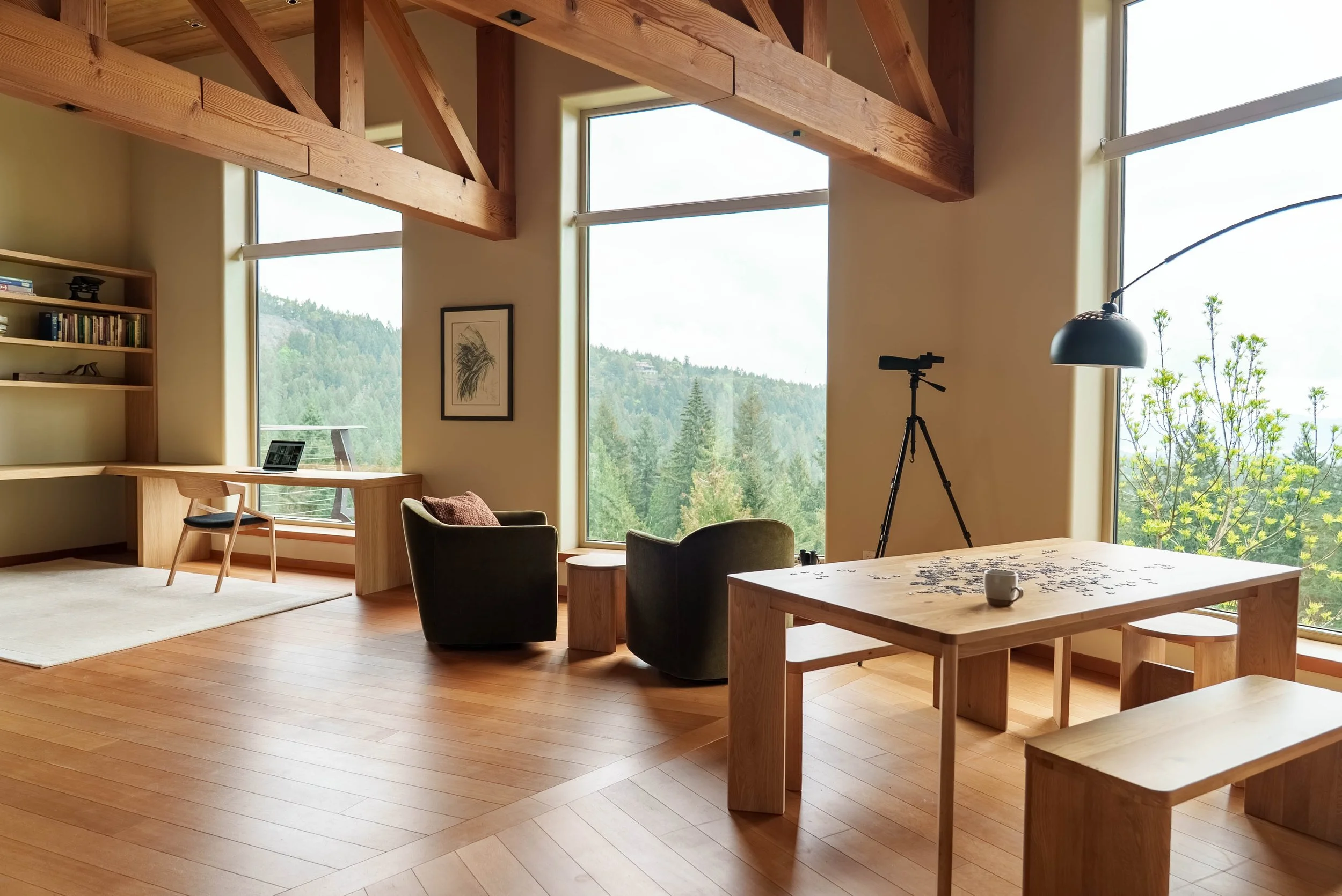 Wide-angle view of a warm, contemporary great room on Salt Spring Island, featuring an oak dining table by Sundays Furniture, custom cabinetry, natural materials and quiet luxury interiors by Amber Jordan Design.