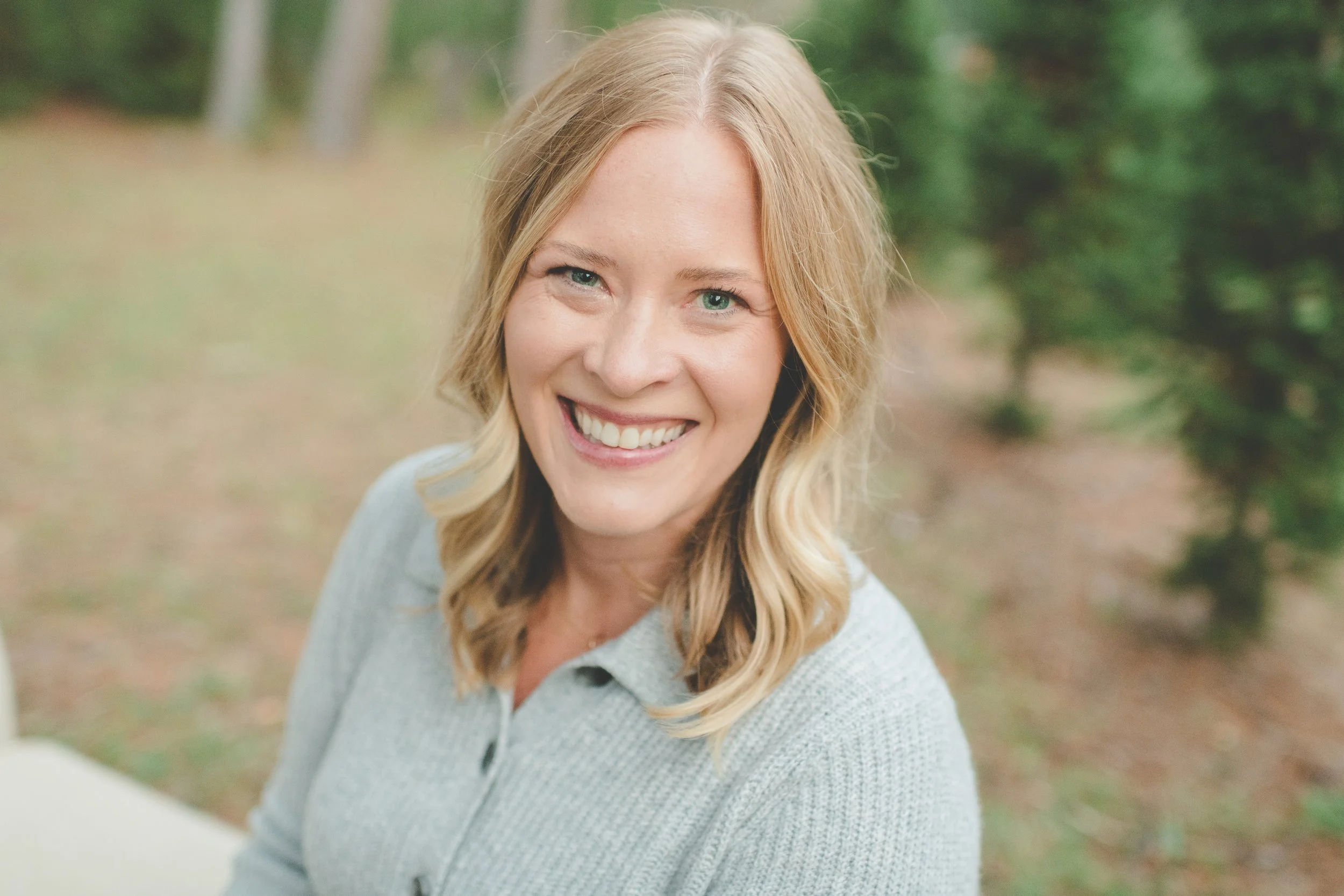 Smiling woman with blond hair outdoors.