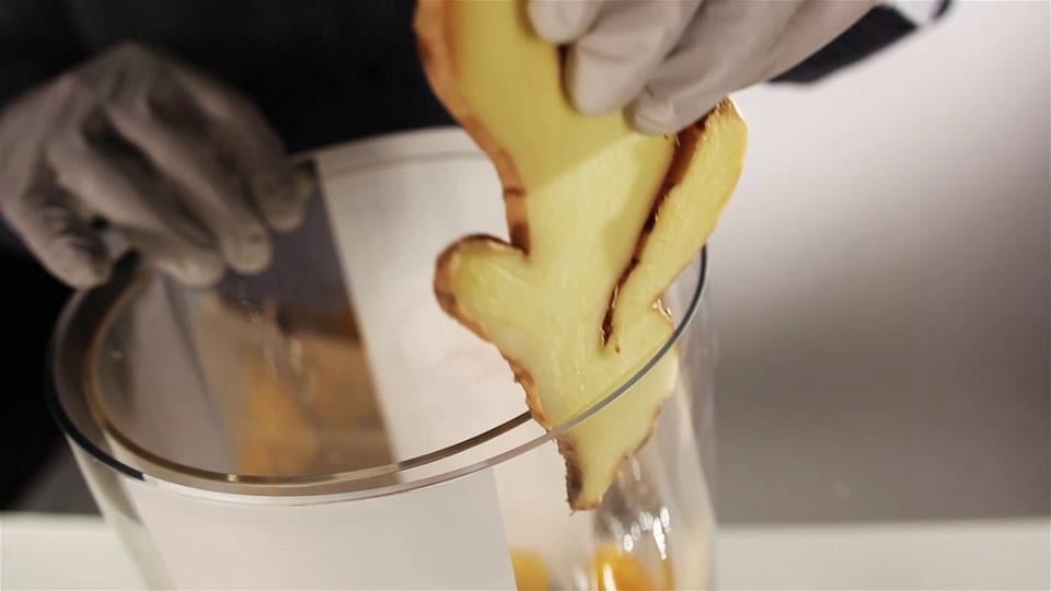 Inserting a slice of fresh ginger into CQ's Patented Infused Beverage System. The ginger is held in place because it is positioned between the inner wall of the beverage dispenser and the outer wall of the insert, thereby eliminating blocked faucets.