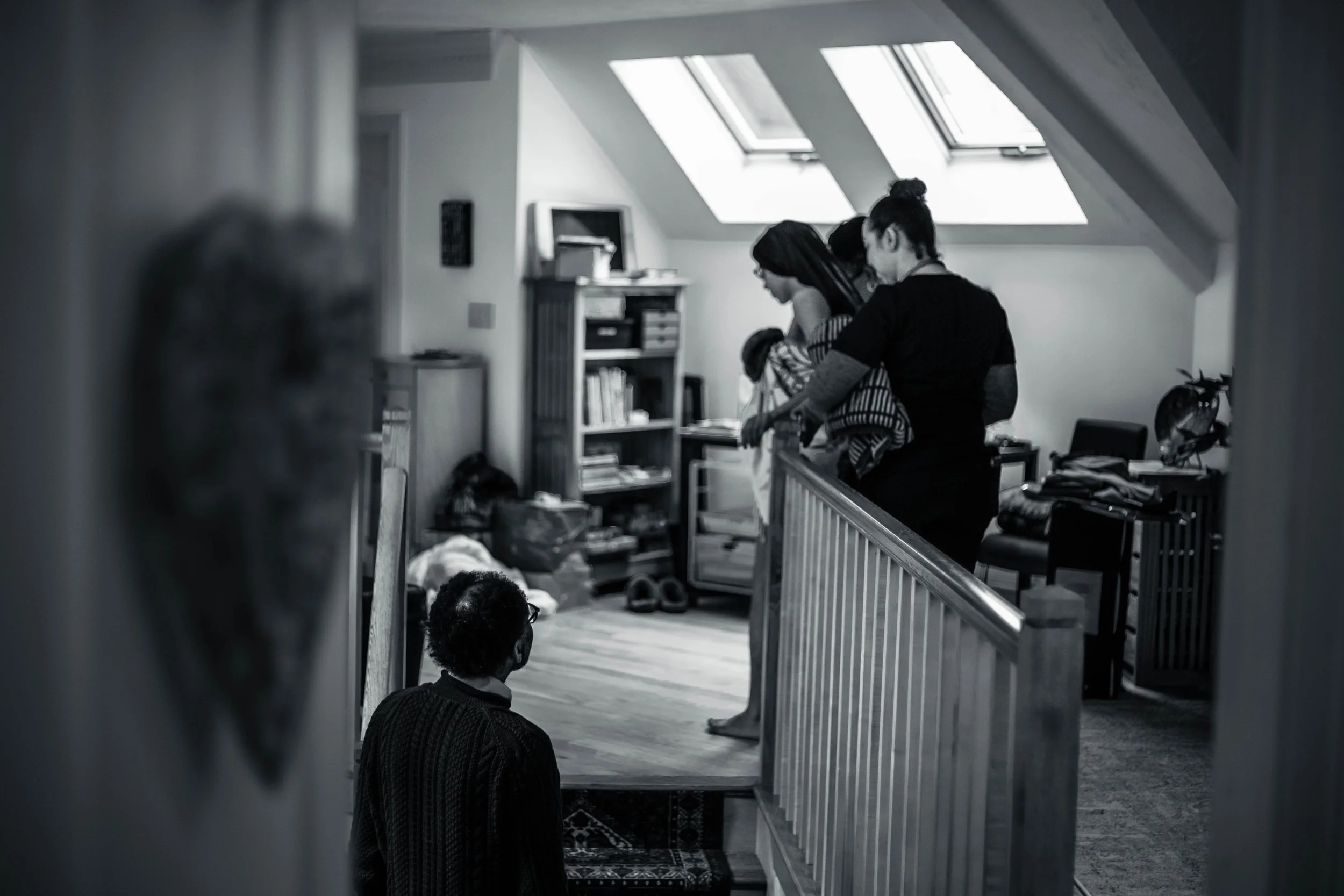 Family watches as mother walks past a staircase