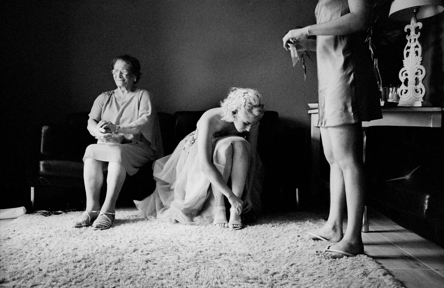 abuela, novia y hermana de la novia preparándose antes de la ceremonia en una habitación, escena documental en blanco y negro