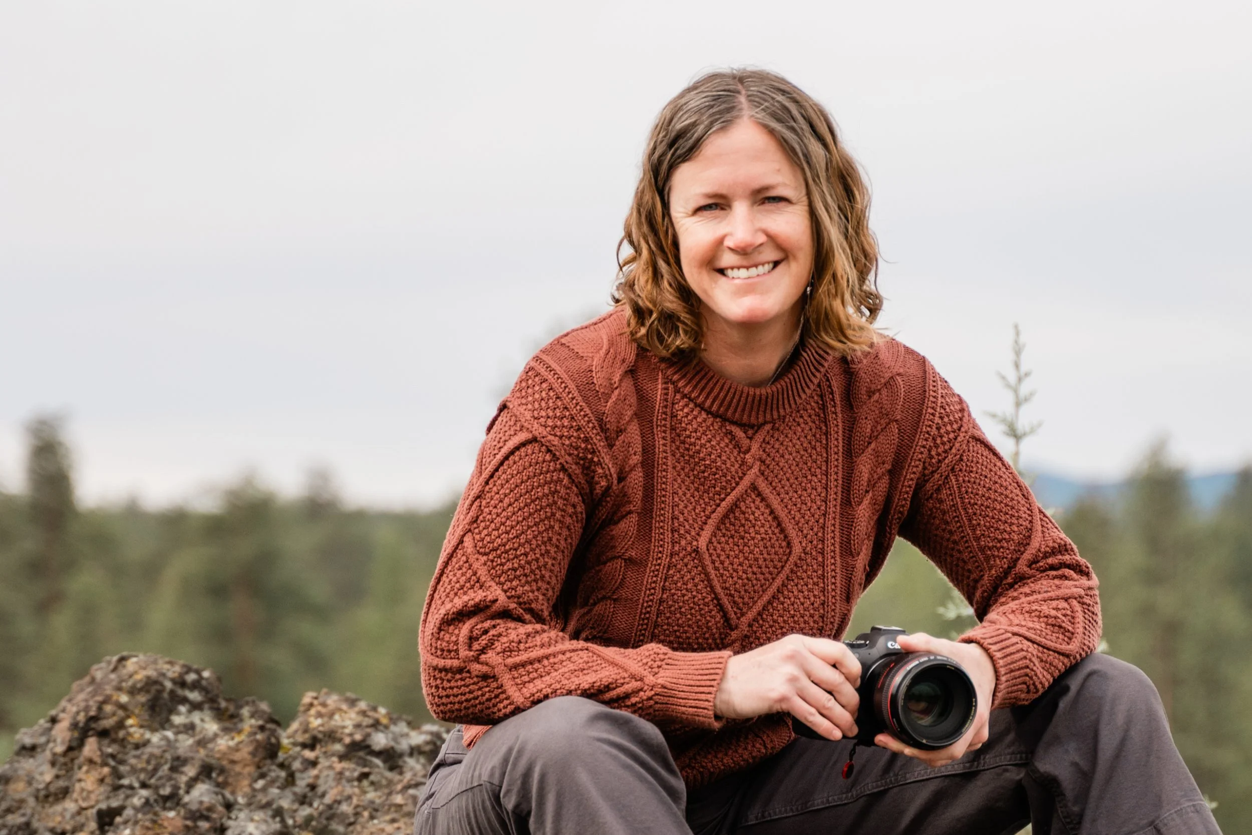 Photographer sitting, smiling, and holding her camera