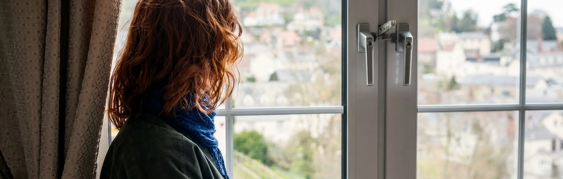 Woman looking thoughtfully out a window after a setback, reflecting and regulating anger and overwhelm with adult ADHD.