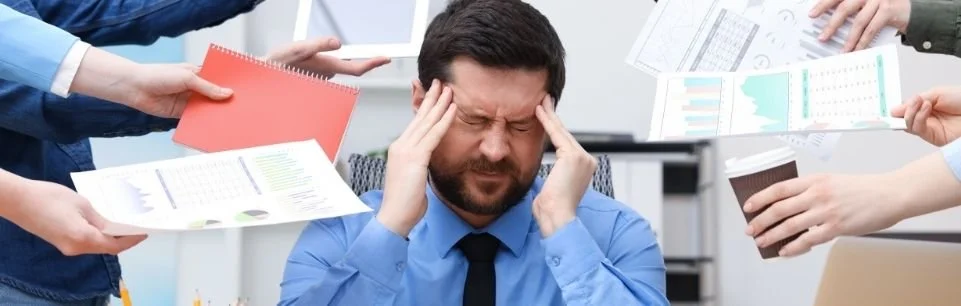 Man with ADHD feeling overwhelmed by multiple tasks and requests at a cluttered desk