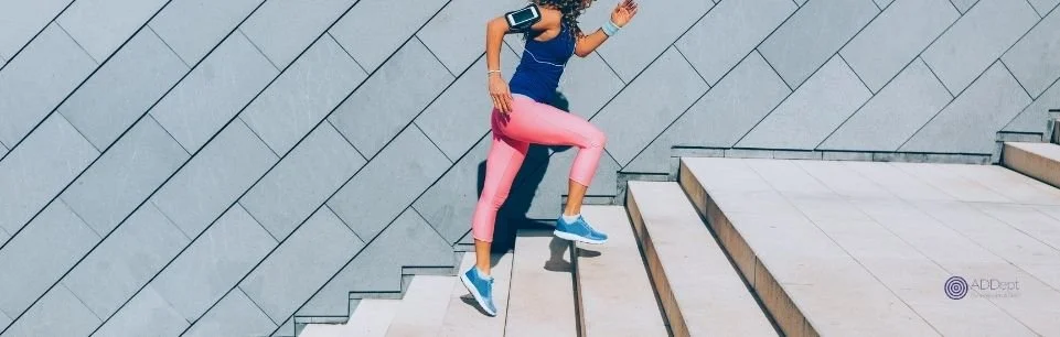 Adult woman jogging up outdoor stairs to build focus, energy, and healthy routines for adult ADHD.