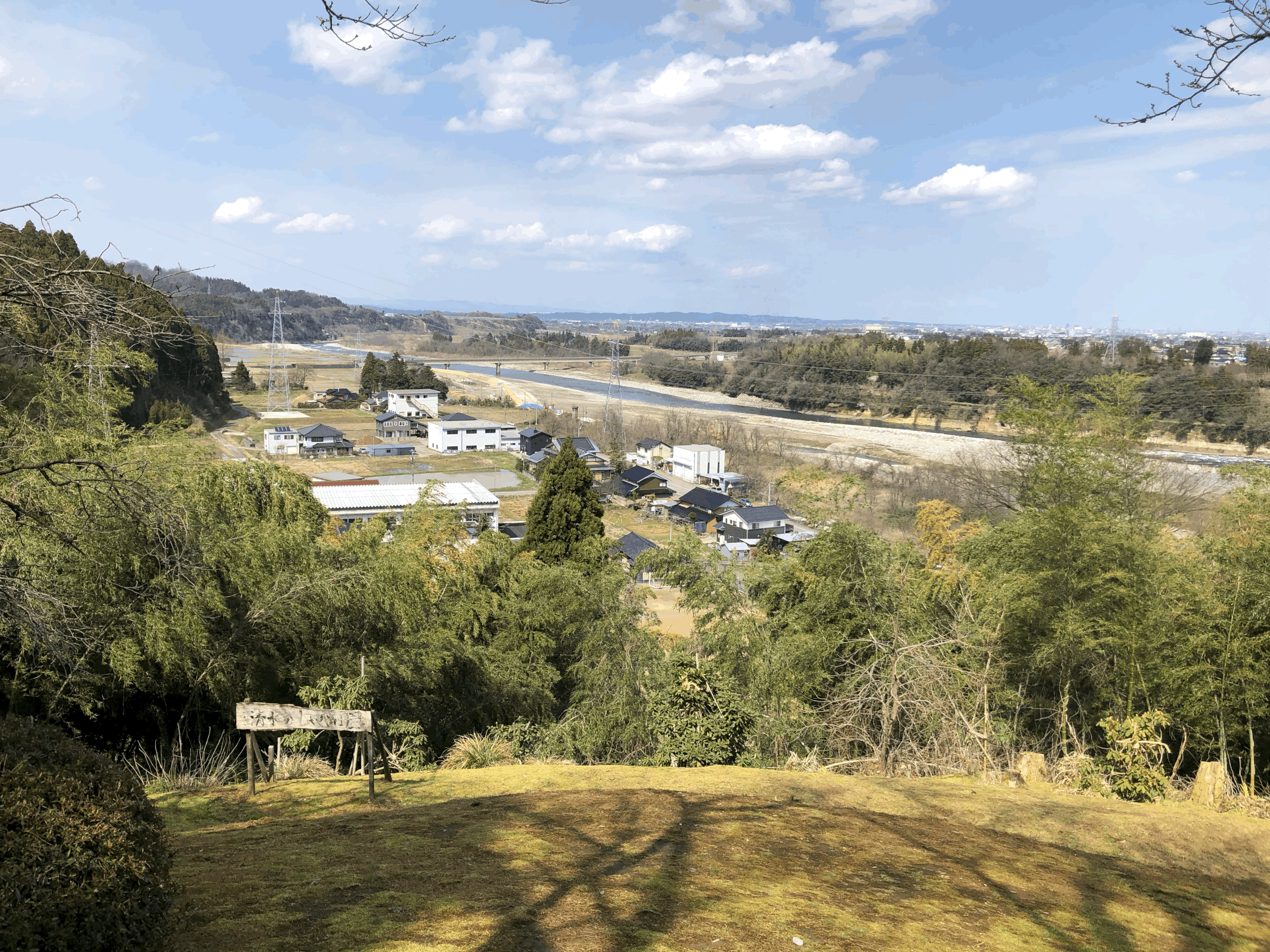 裏山からの風景写真(体育館の屋根が見え、その奥には神通川と富山市の風景が広がっています)