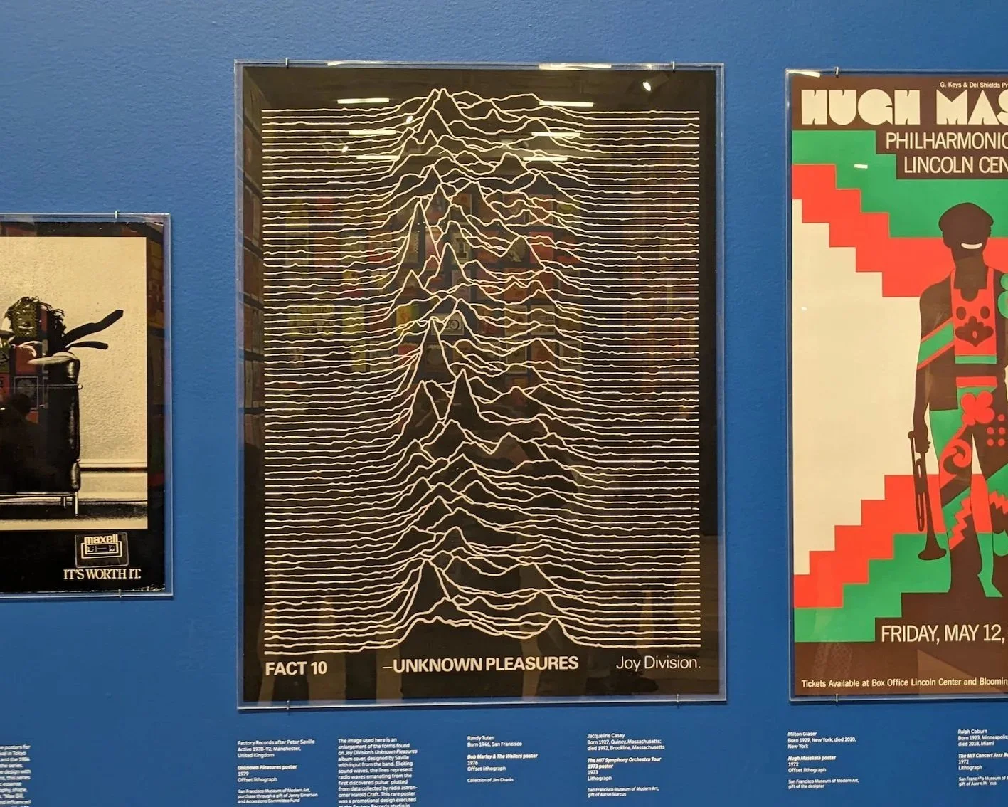 Black-and-white Joy Division poster featuring a series of horizontal waveform lines forming a symmetrical, mountain-like pattern on a dark background.