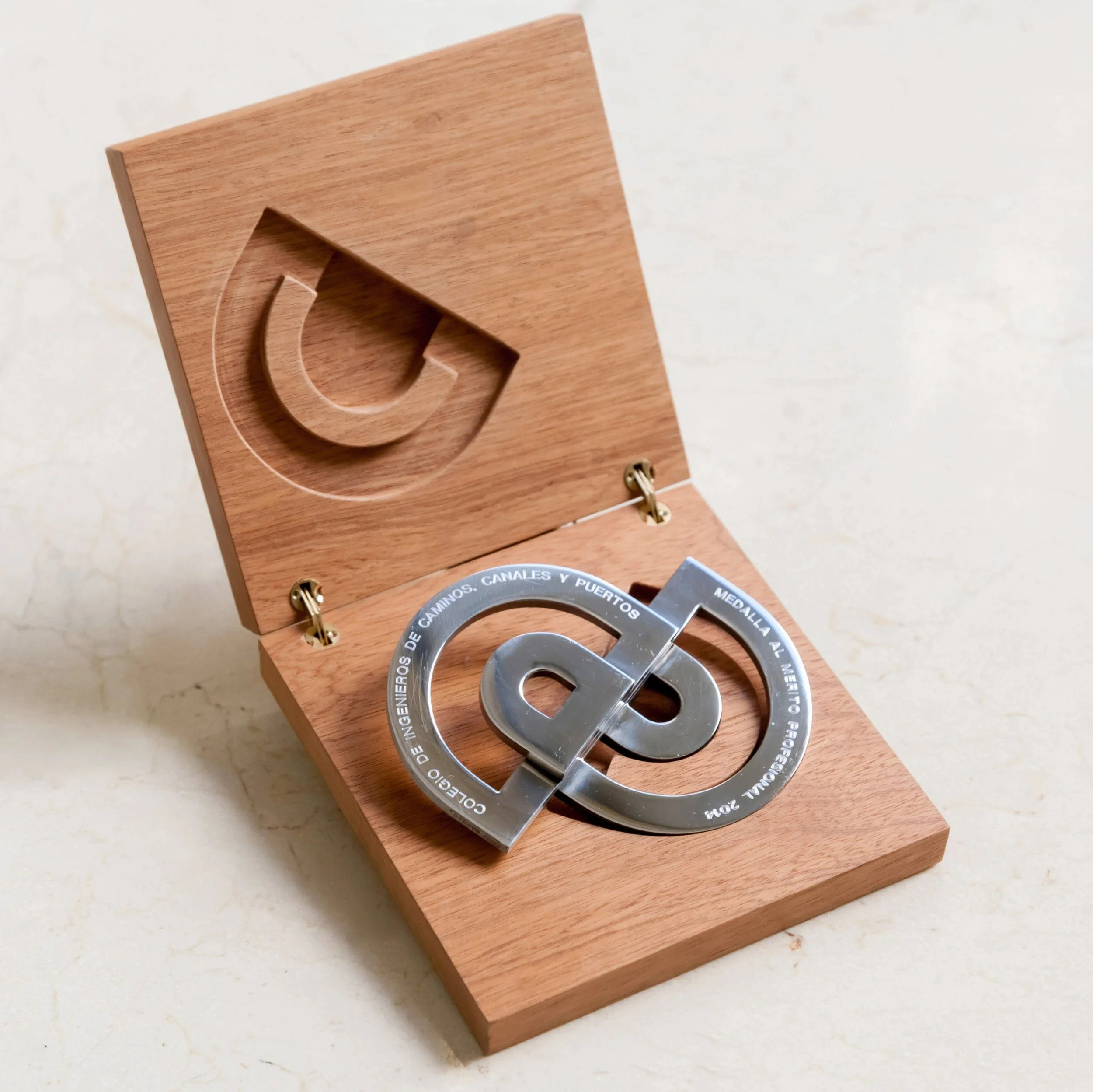 A geometric metal sculpture by José María Cruz Novillo displayed inside an open wooden box.