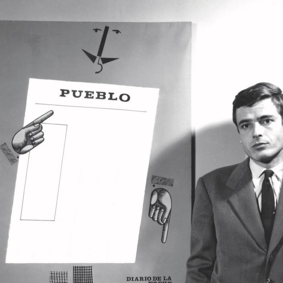 Black-and-white portrait of Spanish designer José María Cruz Novillo standing beside one of his early poster designs featuring the word “PUEBLO,” abstract facial elements, and pointing illustrated hands.
