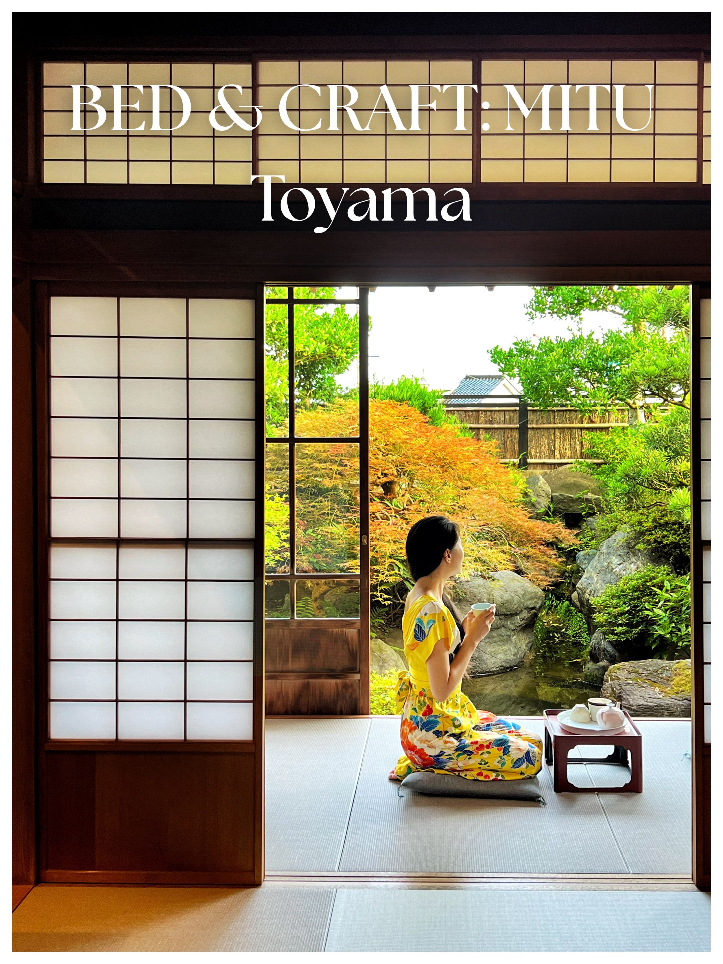 A woman in a colorful yukata sits on a cushion in a traditional Japanese tatami room, enjoying tea while looking at a Japanese garden with rocks and trees outside.