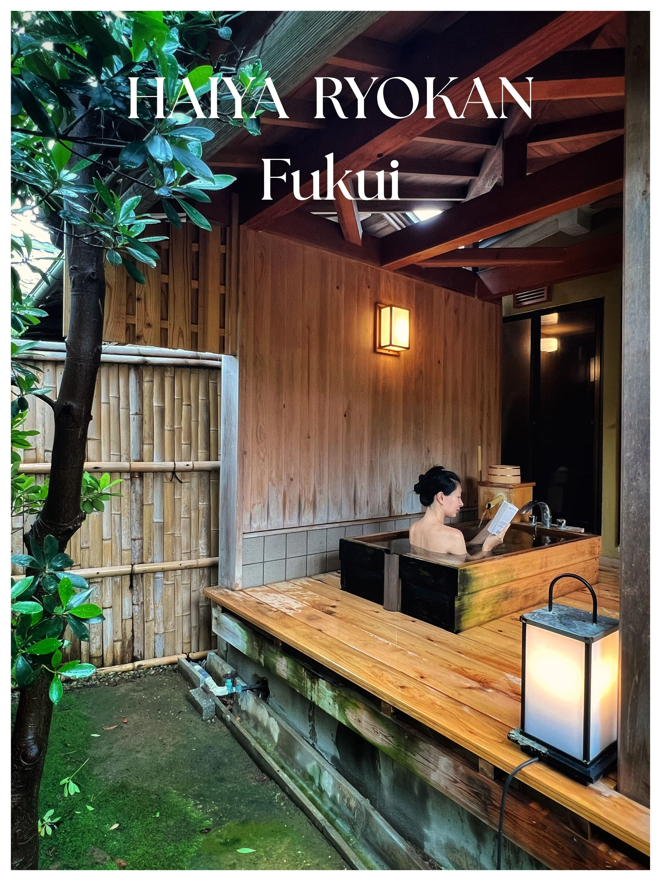 A woman relaxing in a traditional wooden Japanese outdoor bath, or onsen, surrounded by greenery with a bamboo fence.