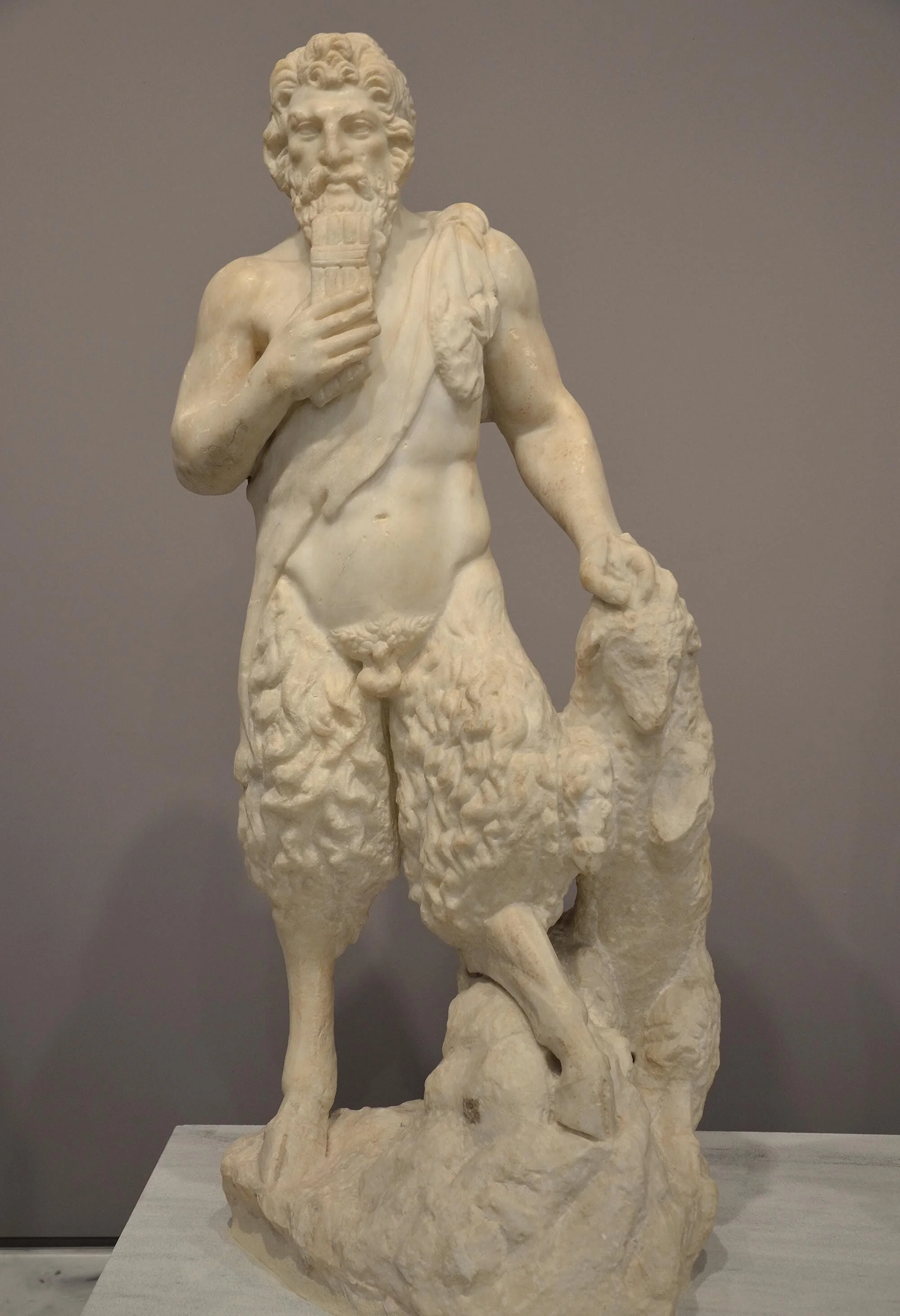 A marble statue of the god Pan holding panpipes