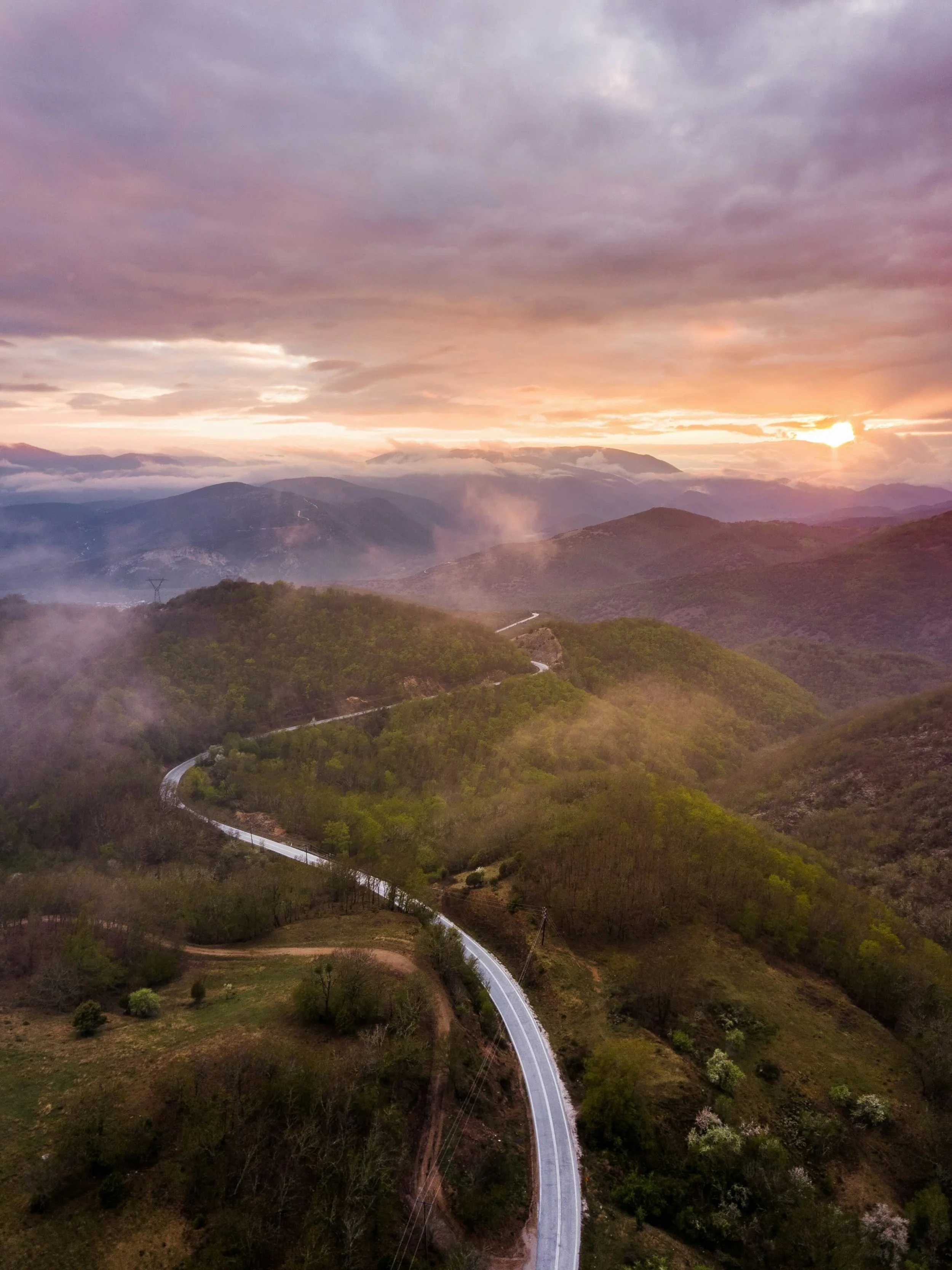 A road curving through a landscape of forest and mountains