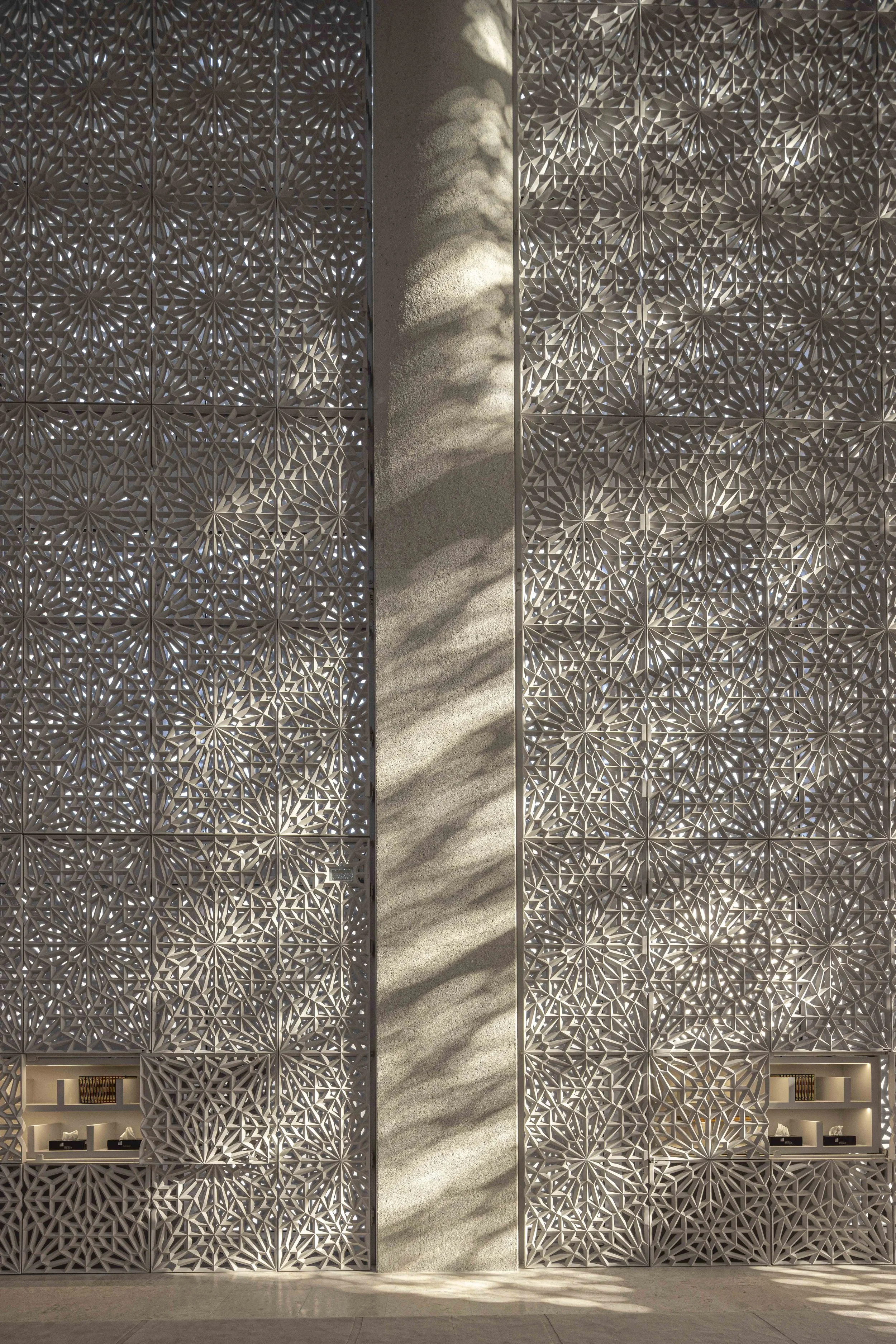 Carved mashrabiya lattice wall with diagonal shadows inside the Imam Ahmed Al-Tayeb Mosque, Abrahamic Family House, Abu Dhabi. Architect Adjaye Associates