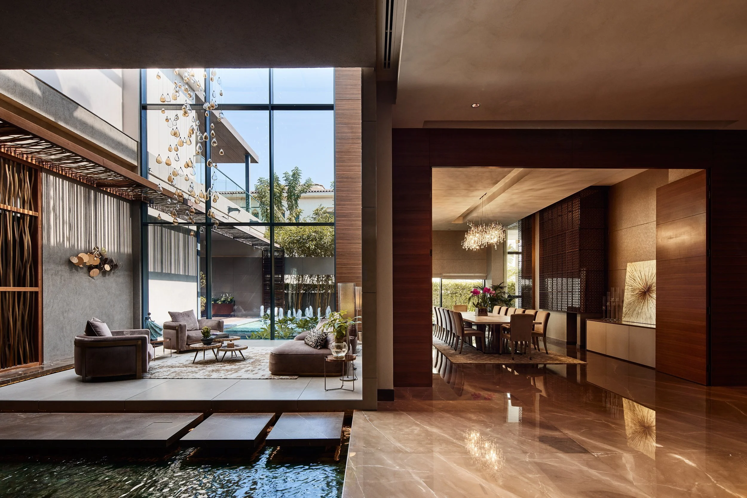Living room and dining area of M Villa seen across a water terrace, Dubai Hills Estate