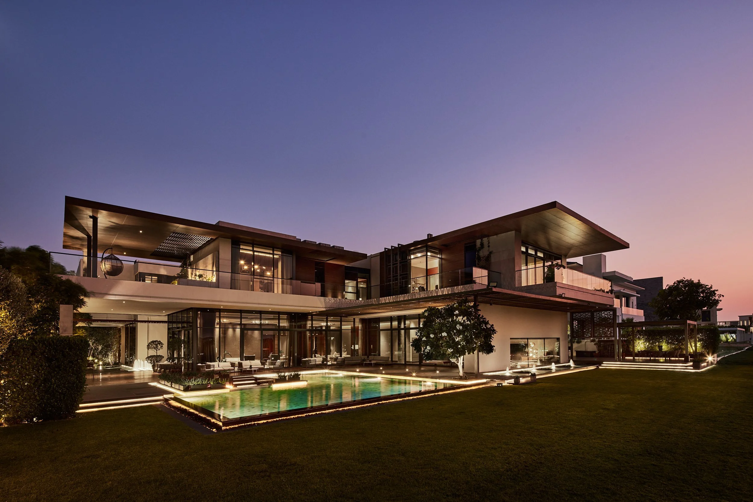 Courtyard fountains lit at night between glass and stone wings of M Villa, Dubai Hills Estate