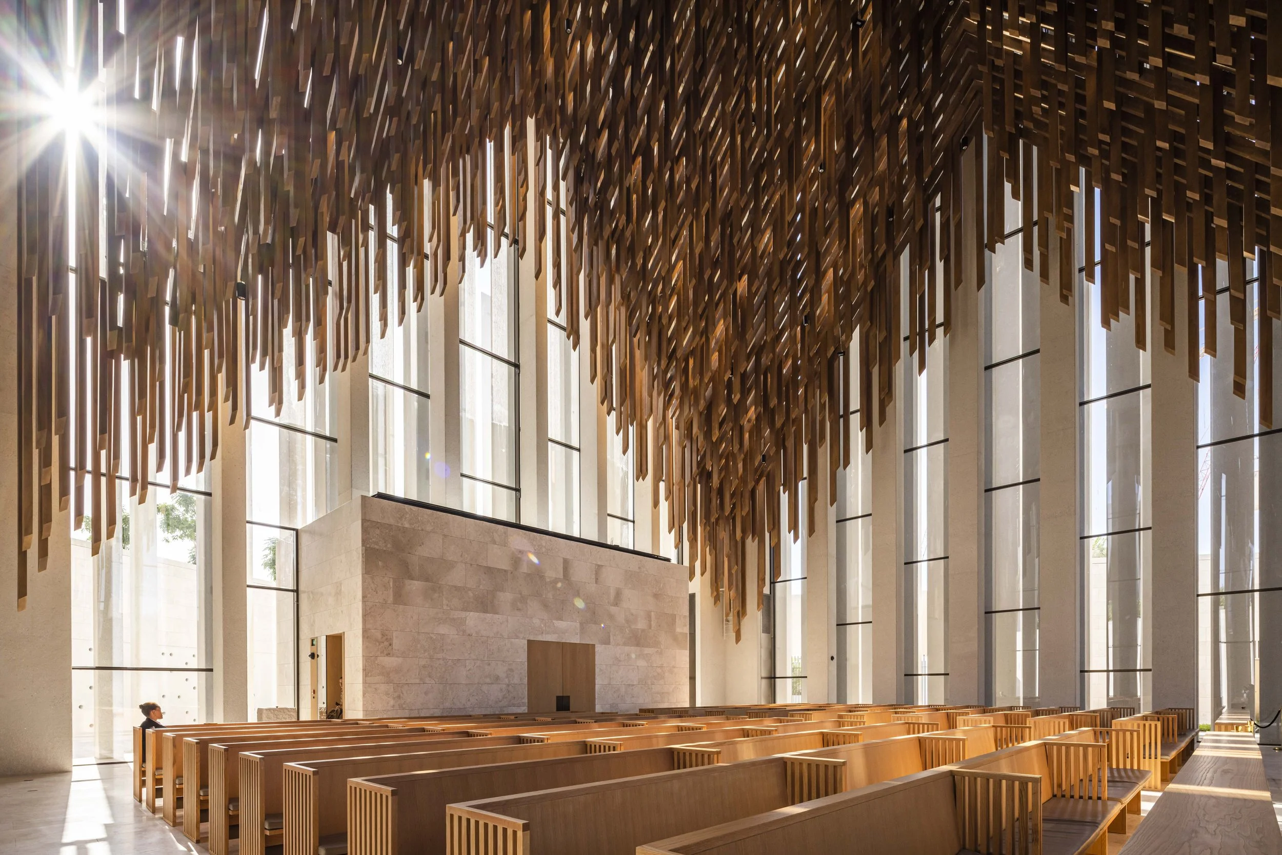 Hanging timber battens above pews inside St. Francis Church, Abrahamic Family House, Abu Dhabi. Architect Adjaye Associates