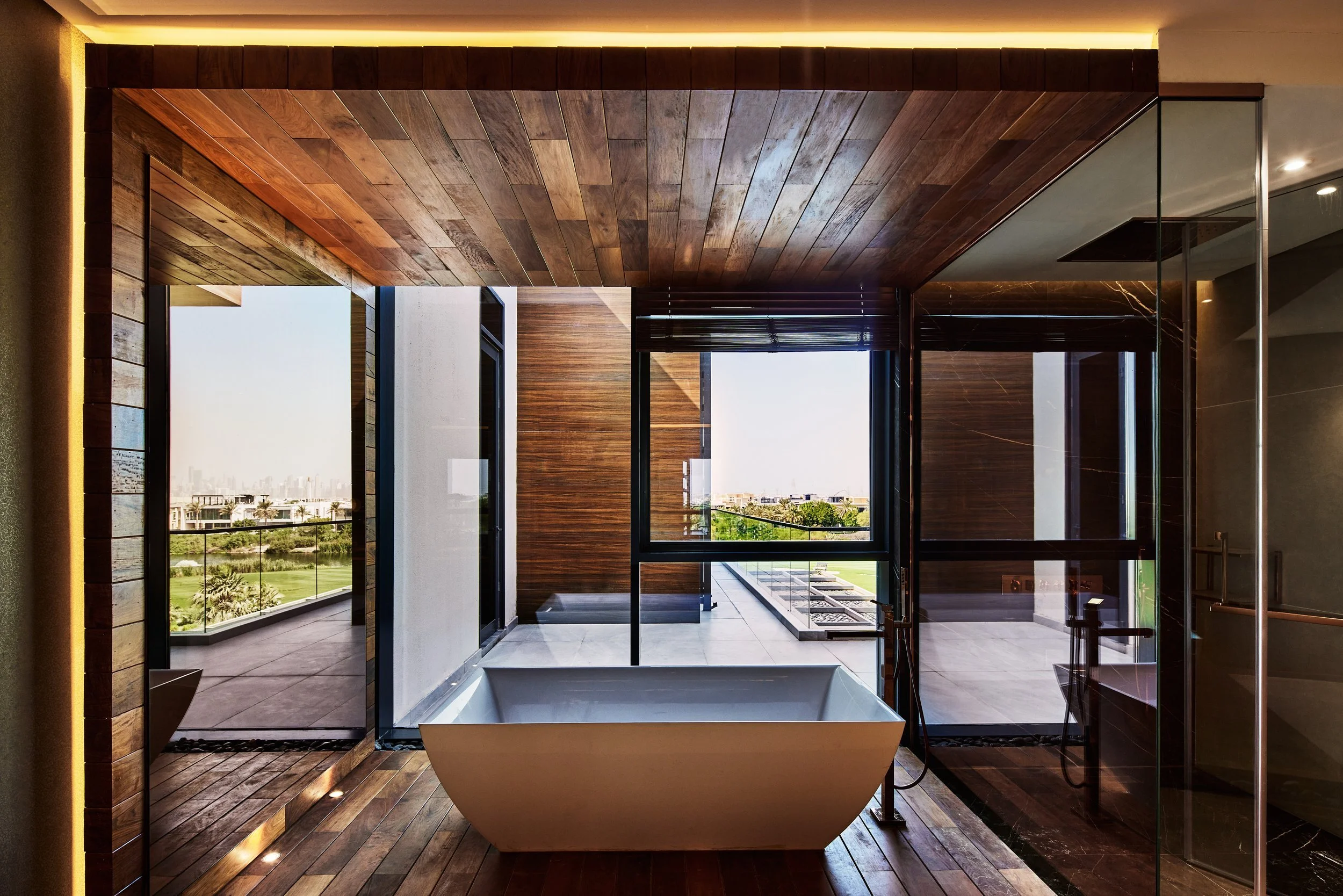 Master bathroom with a freestanding bath under a timber ceiling opening to the garden, M Villa, Dubai Hills Estate