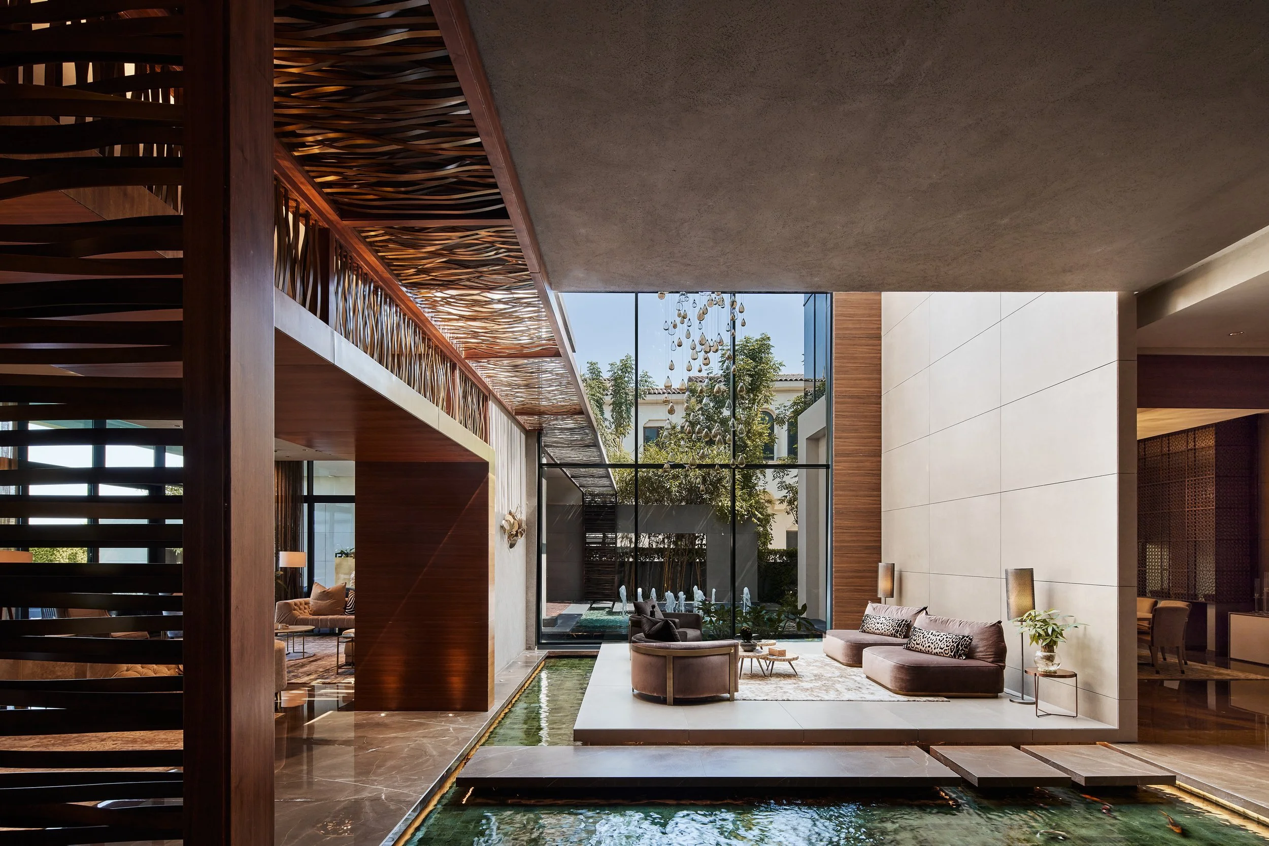 Open living area with low sofas looking onto a courtyard and reflecting pool, M Villa, Dubai Hills Estate