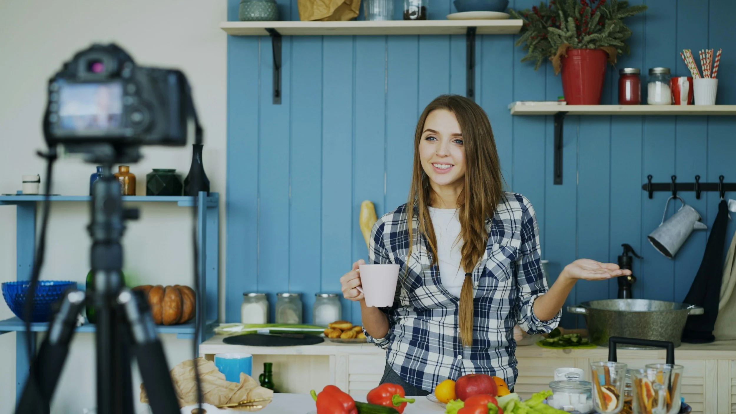 Vrouw die kookt en filmt voor een opnamestudio, met groenten op het aanrecht.