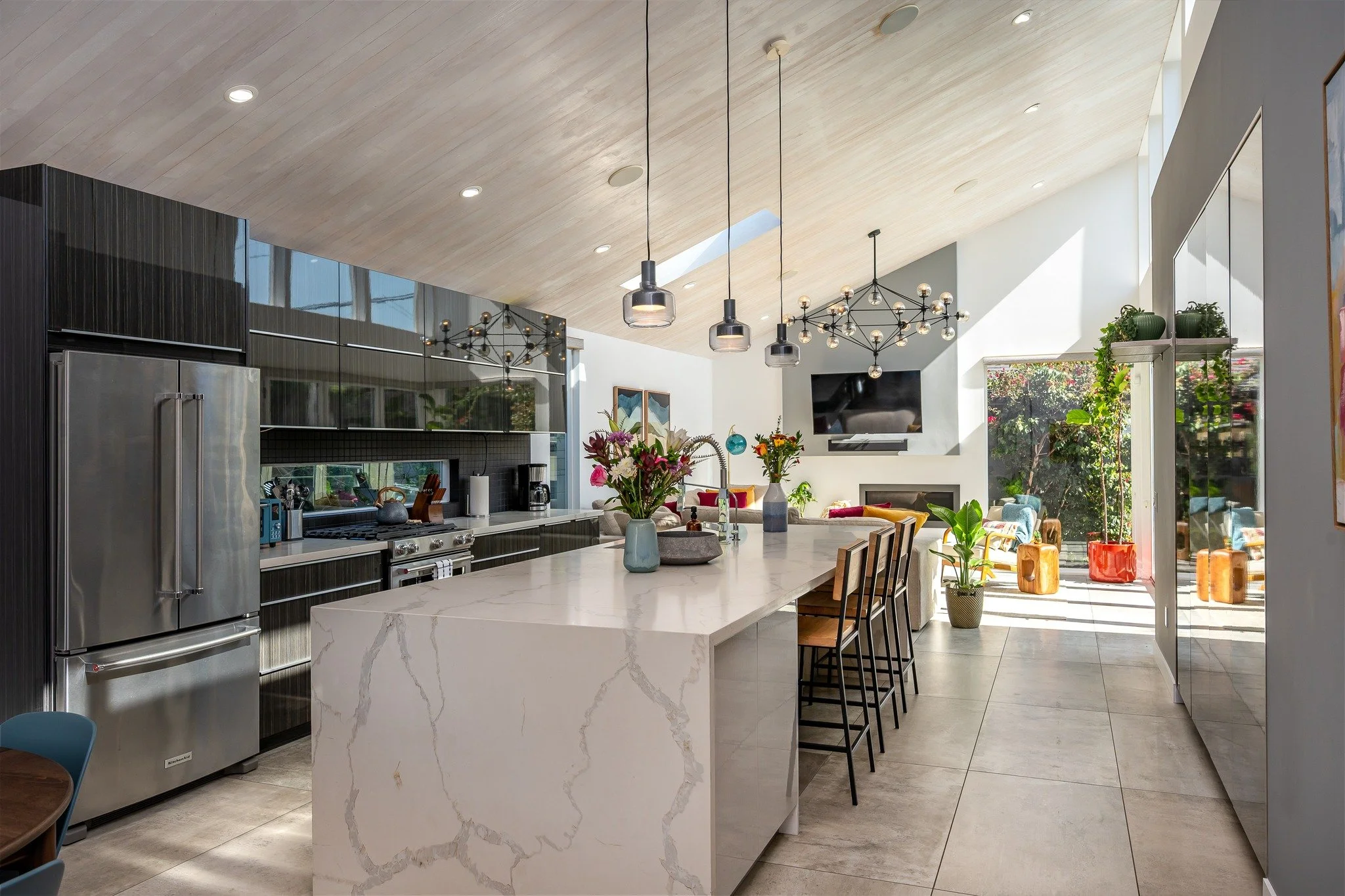 This sleek LA home redefines modern living. The custom kitchen flows effortlessly into the living room, leading to a full-width folding door system that opens to a sun-soaked outdoor deck. Add in the angled ceiling and handcrafted finishes, and you&r