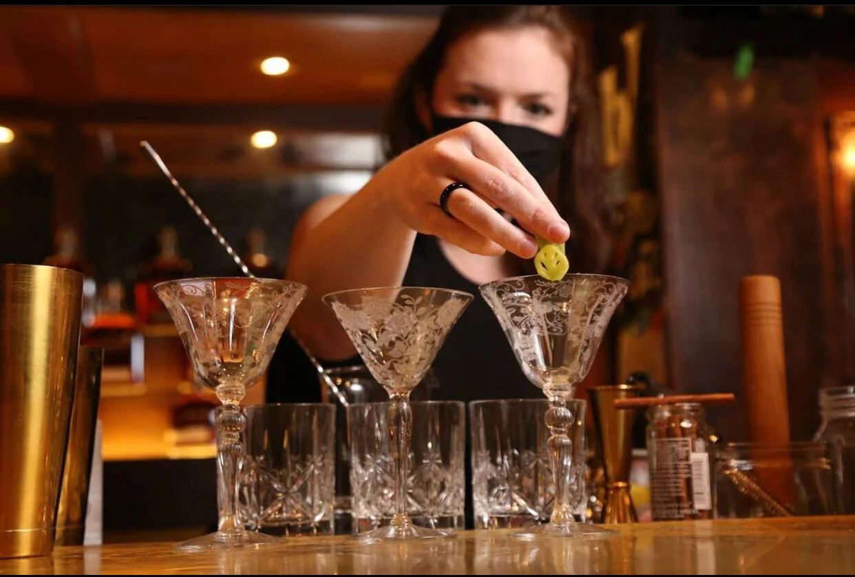 Me applying a garnish to some vintage coupe glasses. You can see some double rocks glasses behind them.