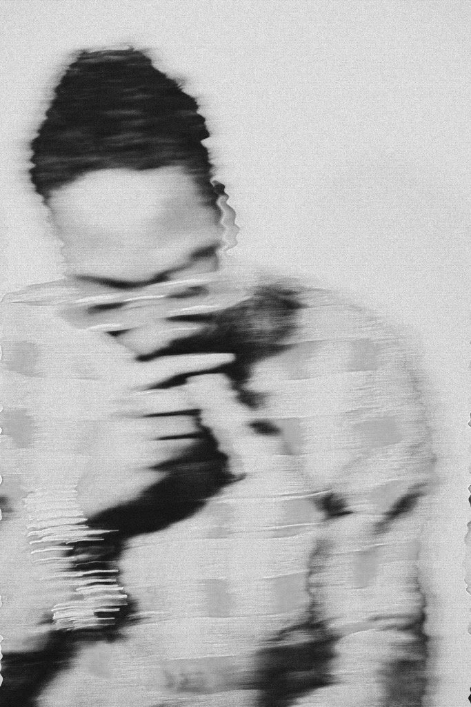 Black and white portrait of a person with a braided hairstyle, holding a phone, with a distorted, glitch effect