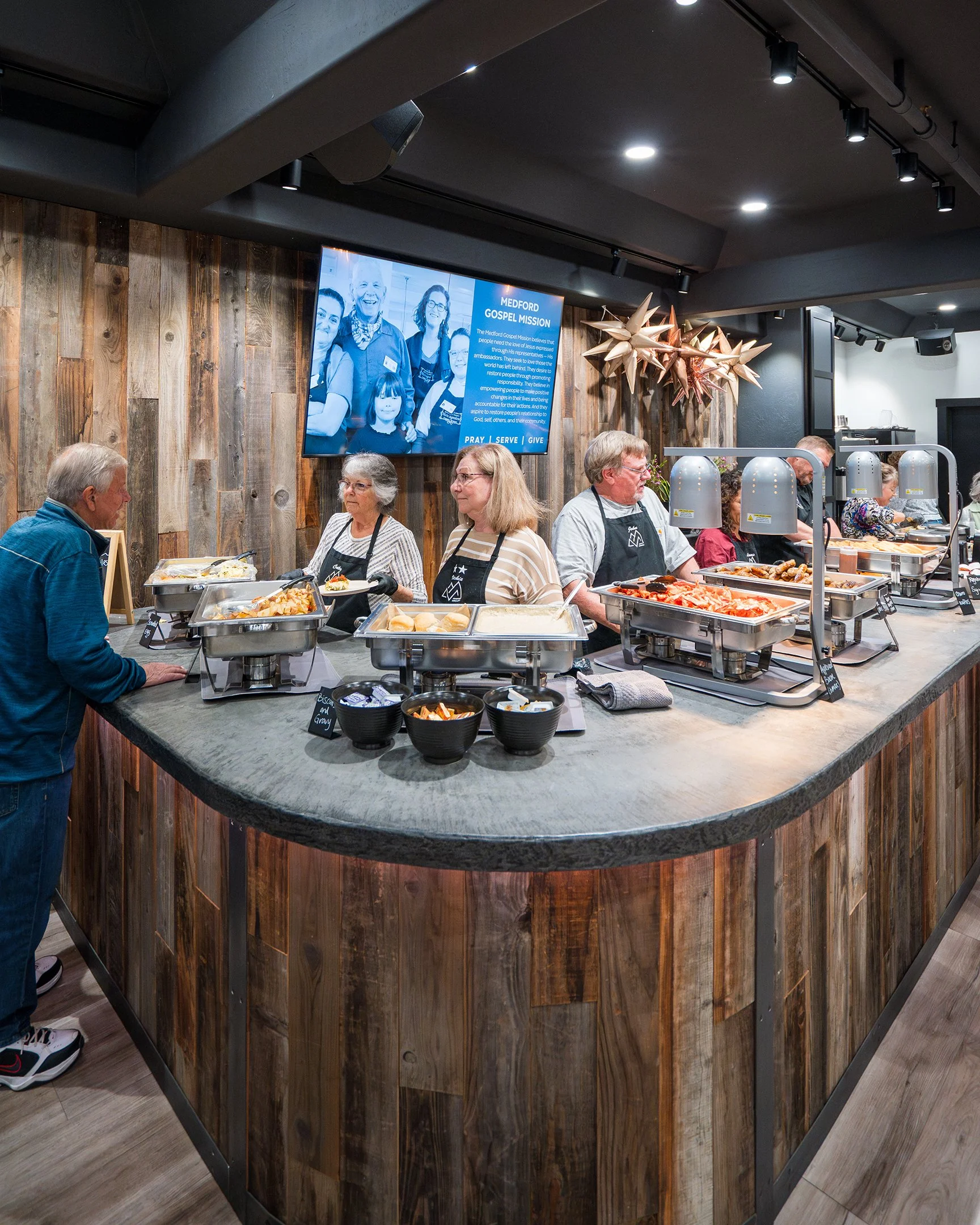 Food servers behind a service bar waiting to serve food to people that have gathered for fellowship