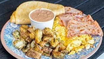 La Mesa Mexican restaurant served customer breakfast plate of eggs, ham, potatoes and tortillas.