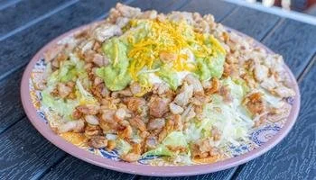 Mexican food restaurant near La Mesa serving plate of meat, beans, guacamole, sour cream, and cheese.