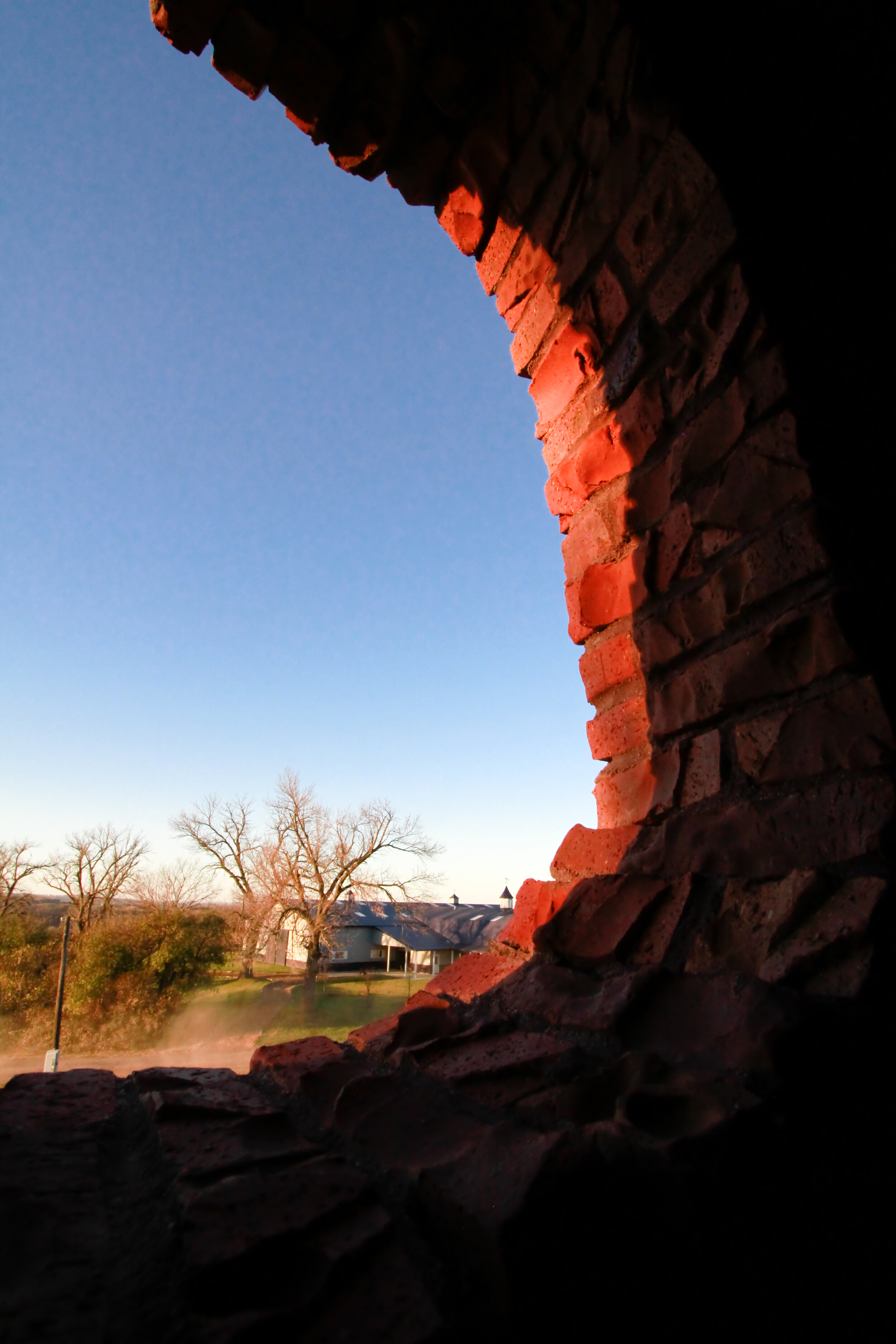 view of farm through silo round window with light on edge