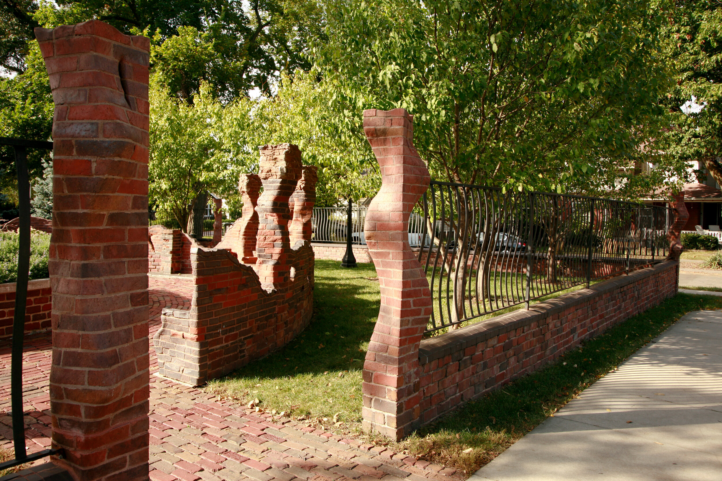 Seven Herms fece and gate of carved red brick in undulation columns surrounds small city park