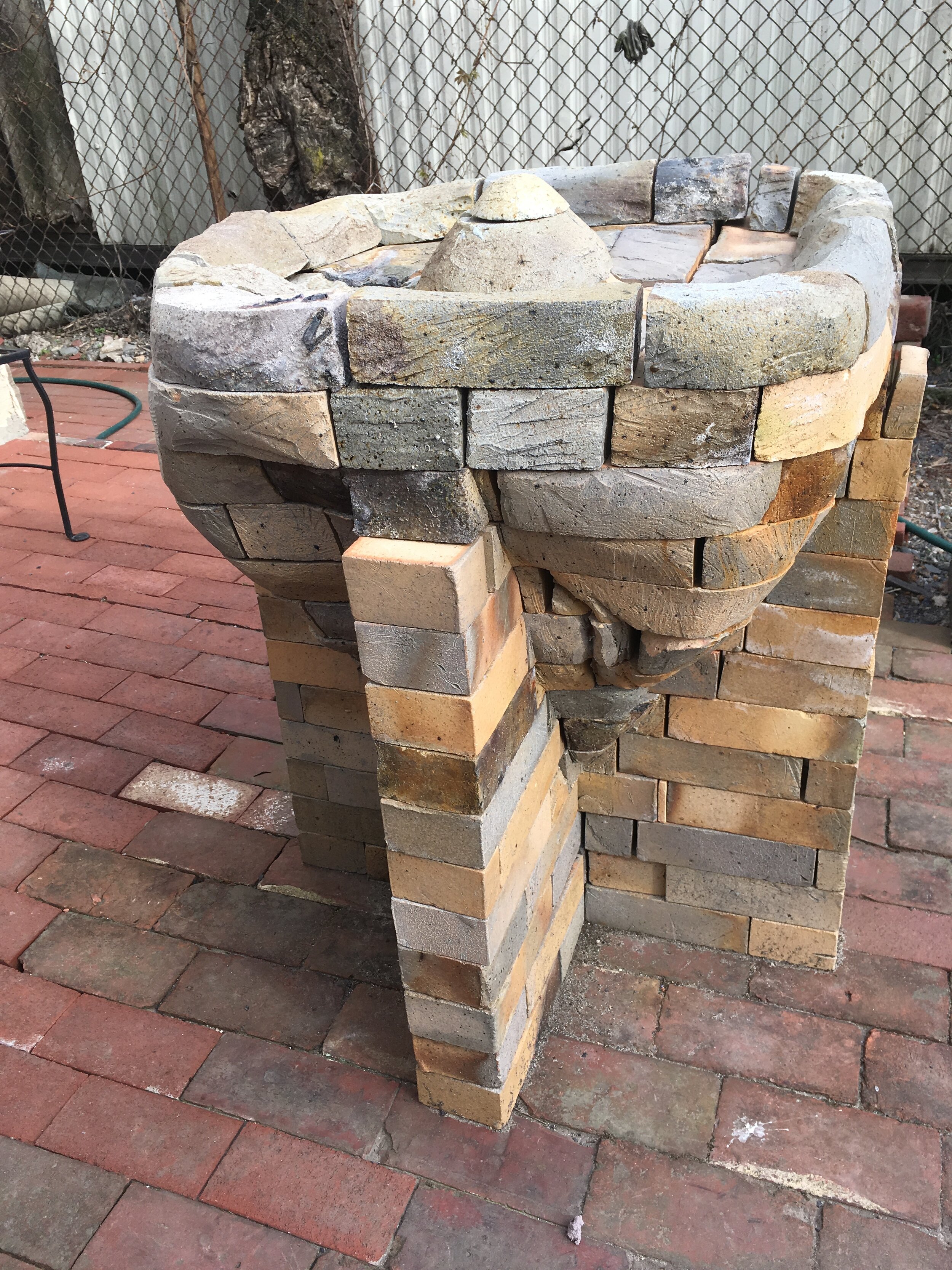 Pillar fountain of carved brick with supporting legs